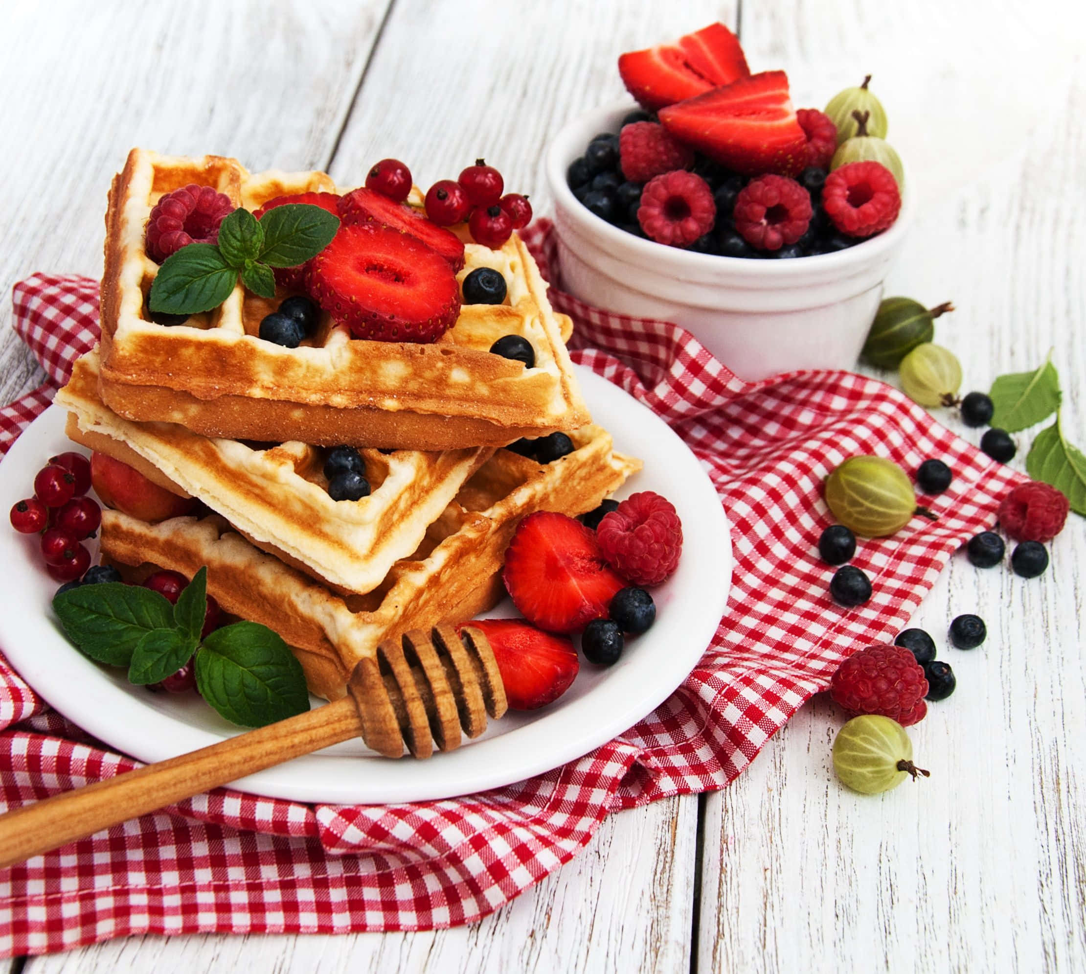 Waffle 桌布 壁紙 — 金黃色窩夫層層疊起，上面放上新鮮莓果和薄荷，放在白色碟上，配以紅色格仔餐巾。