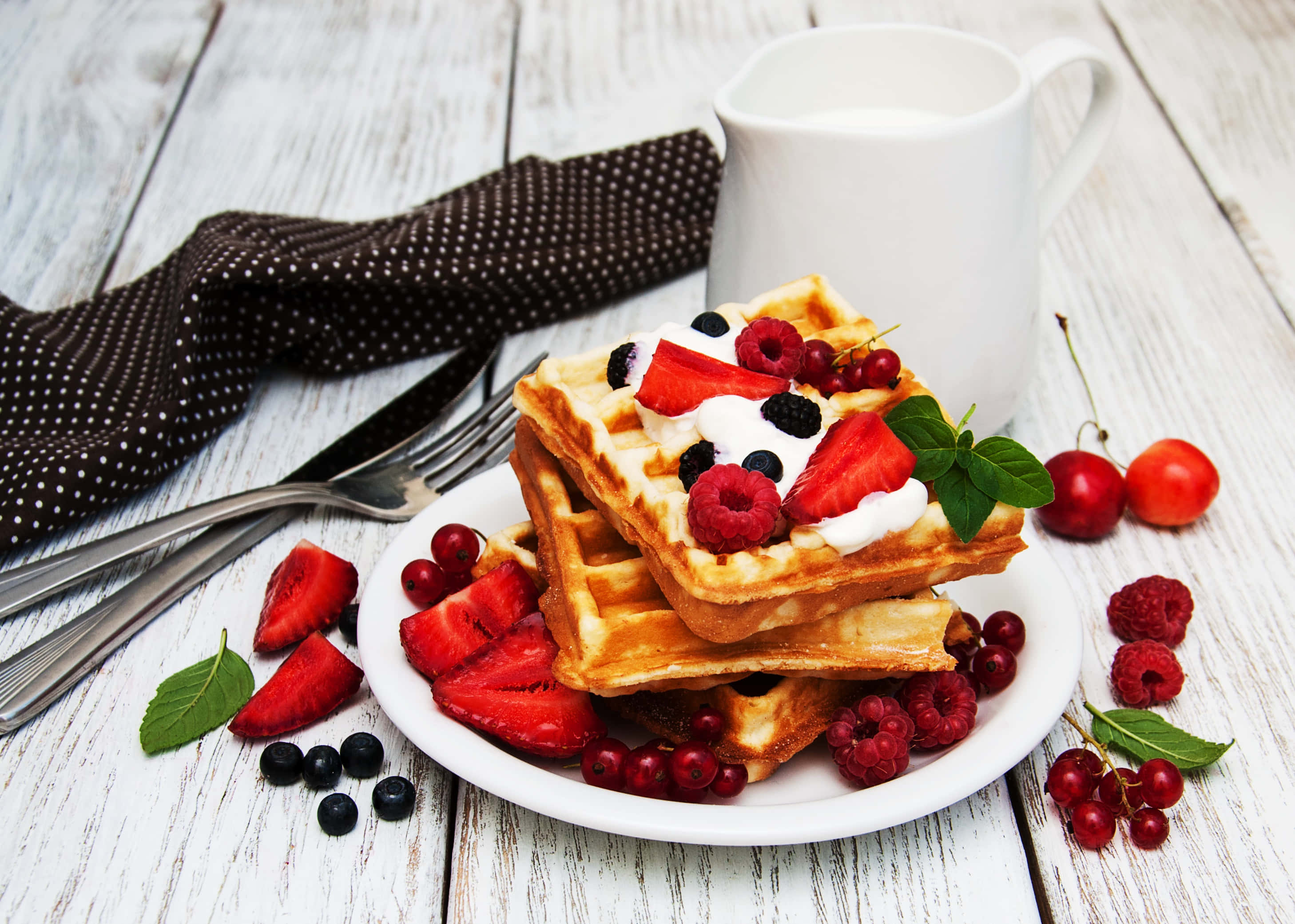 Waffle 桌布 壁紙 — 金黃色窩夫層層疊起，上面鋪滿新鮮莓果、忌廉和薄荷，放在質樸的白色木桌上。