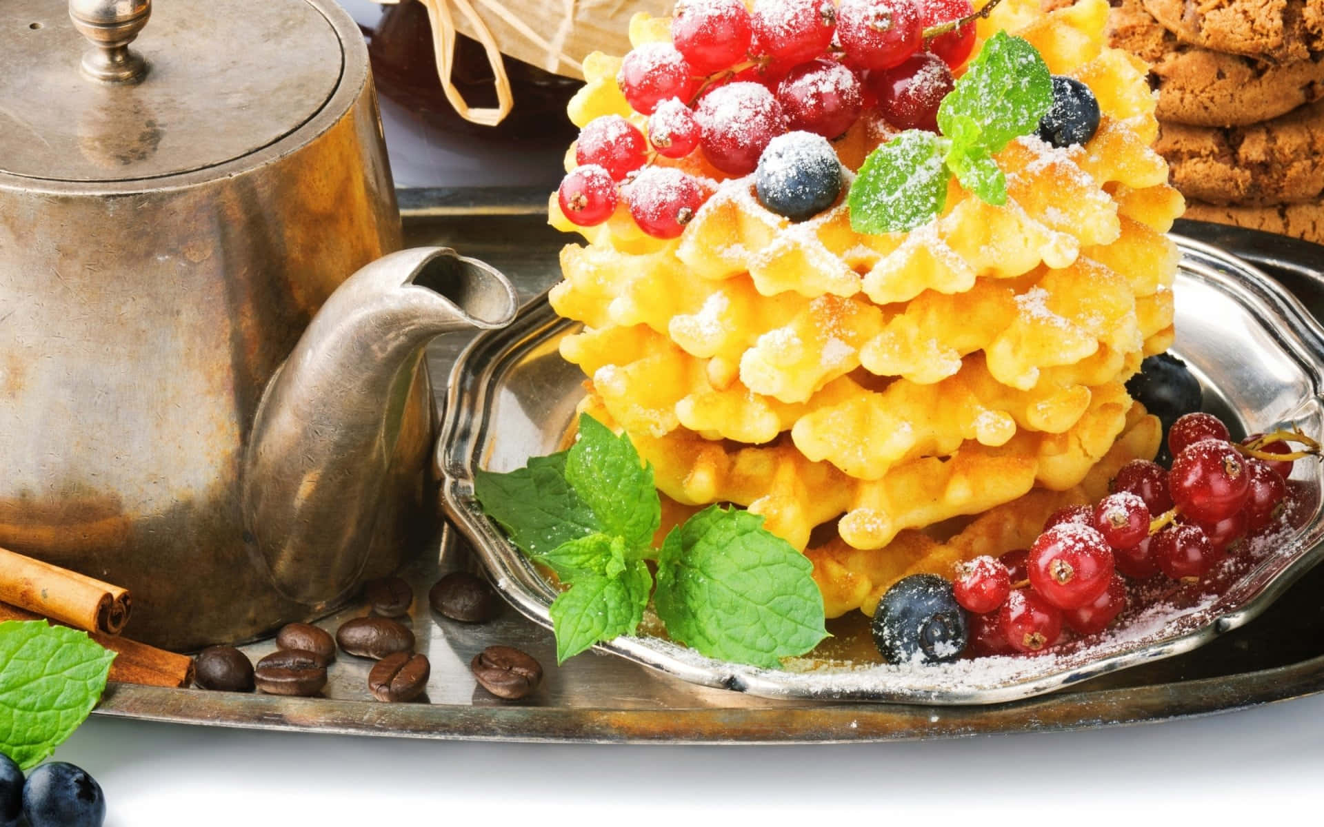 Waffle 桌布 壁紙 — 金黃色窩夫層層疊起，撒上糖霜，上面放有紅加侖子、藍莓和薄荷葉，置於銀托盤上，旁邊放有一個復古茶壺。