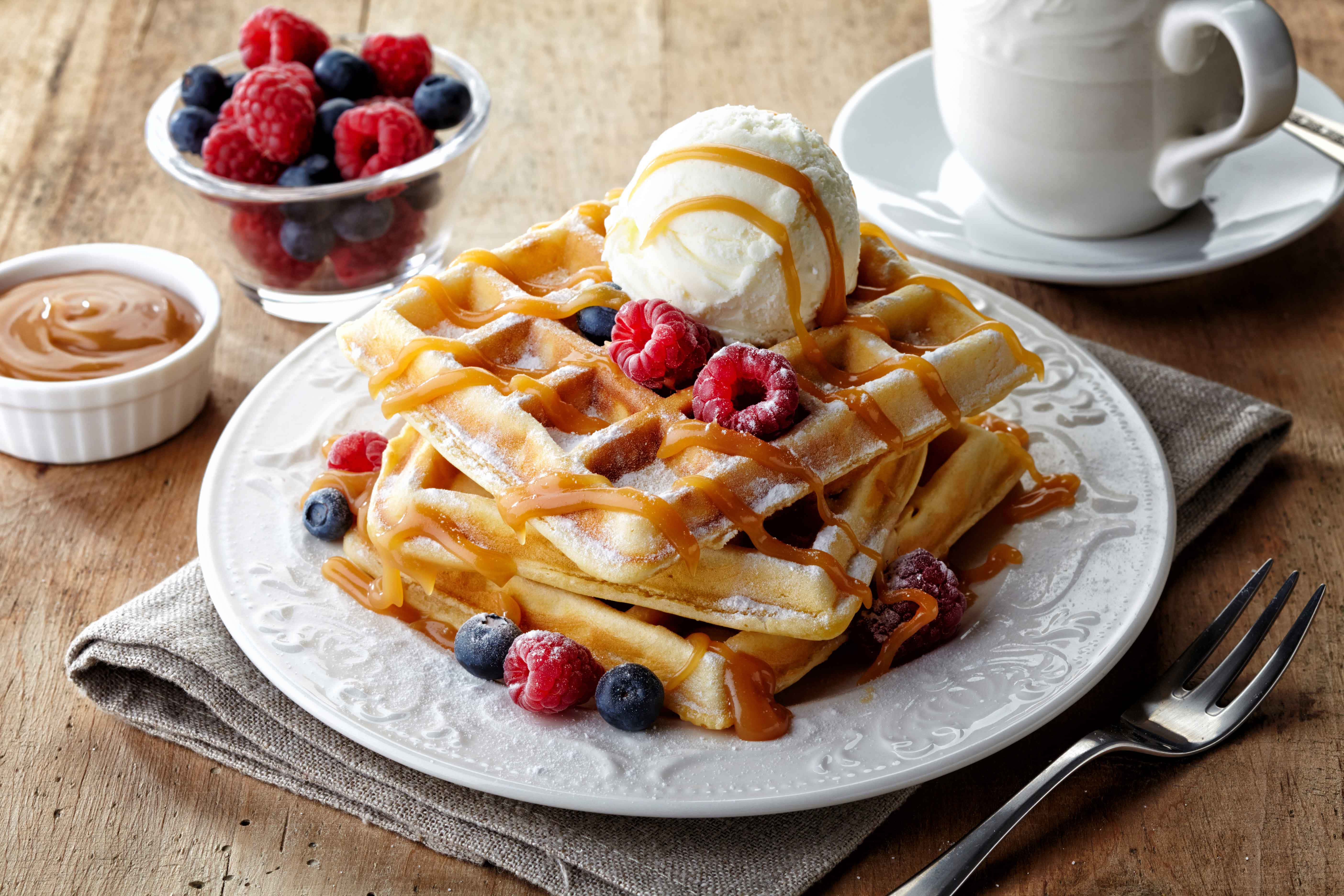 Waffle 桌布 壁紙 — 金黃色窩夫層層疊起，淋上焦糖醬，配上雪糕和新鮮漿果，放在質樸的木桌上。