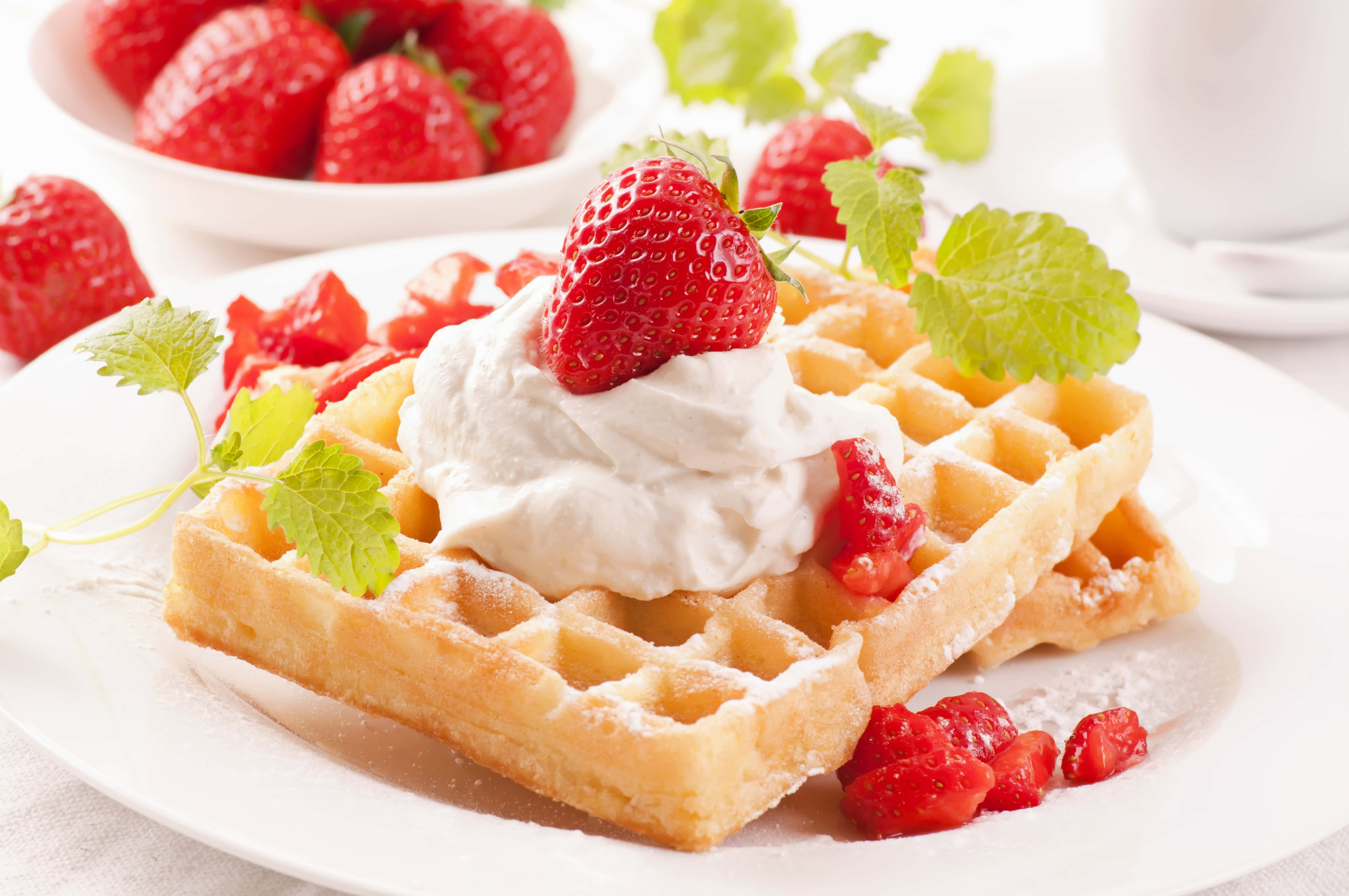 Waffle 桌布 壁紙 — 金黃色窩夫撒上糖霜，配上忌廉和新鮮草莓，並以薄荷葉裝飾。