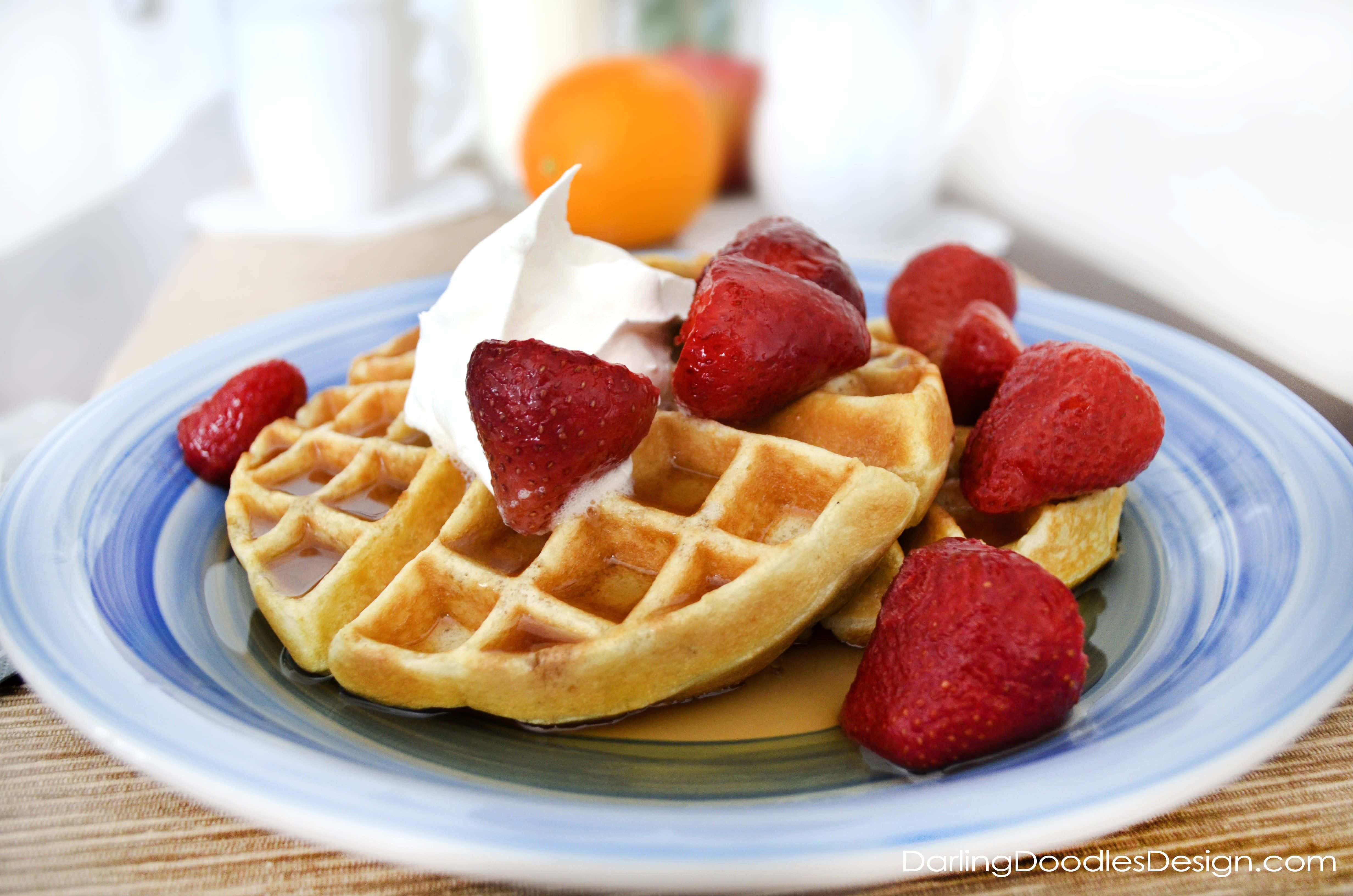 Waffle 桌布 壁紙 — 金黃色窩夫配上新鮮草莓、忌廉和糖漿，放在藍色條紋碟上。