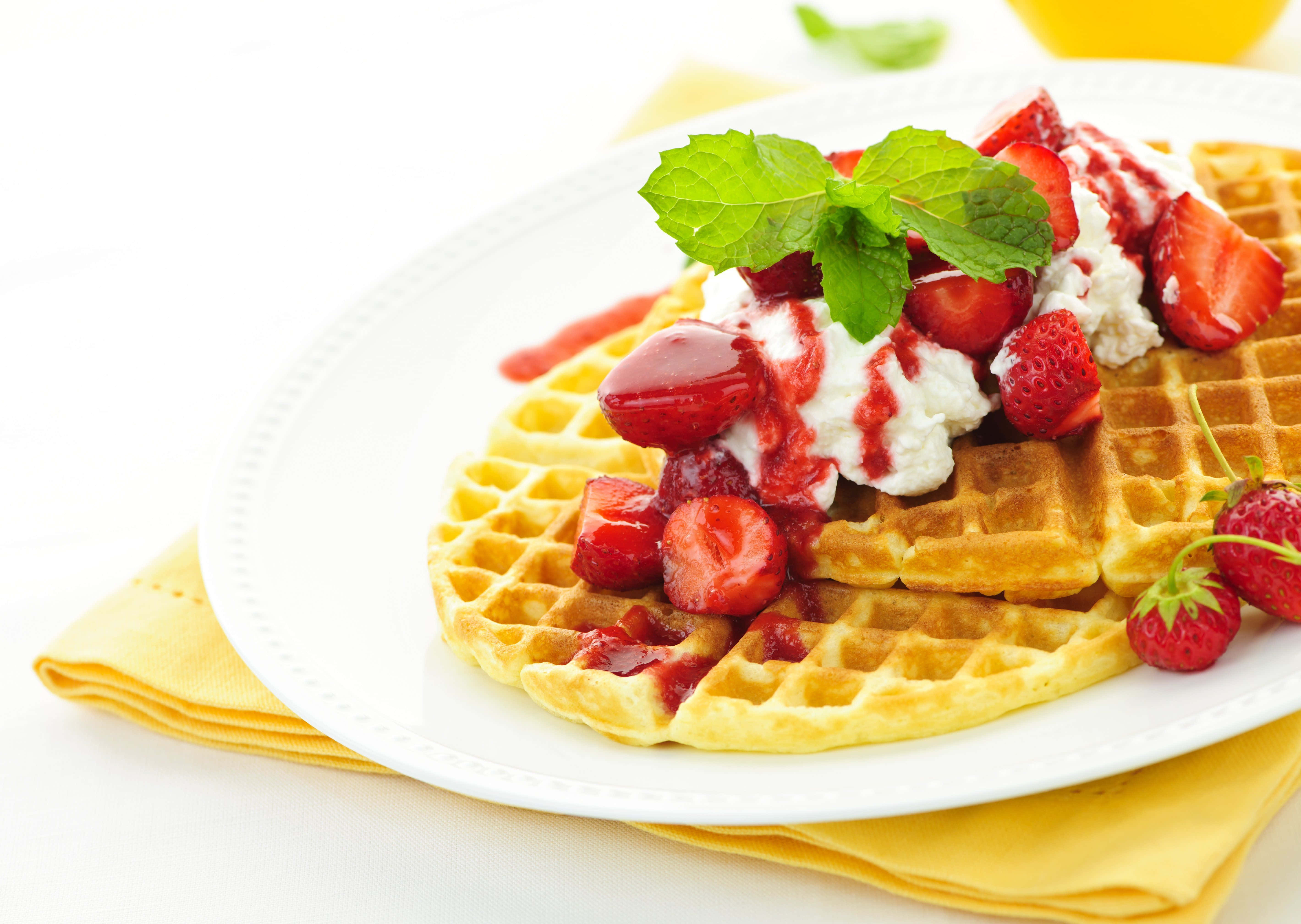 Waffle 桌布 壁紙 — 金黃色窩夫配上新鮮草莓、忌廉和薄荷葉，放在白色碟上。