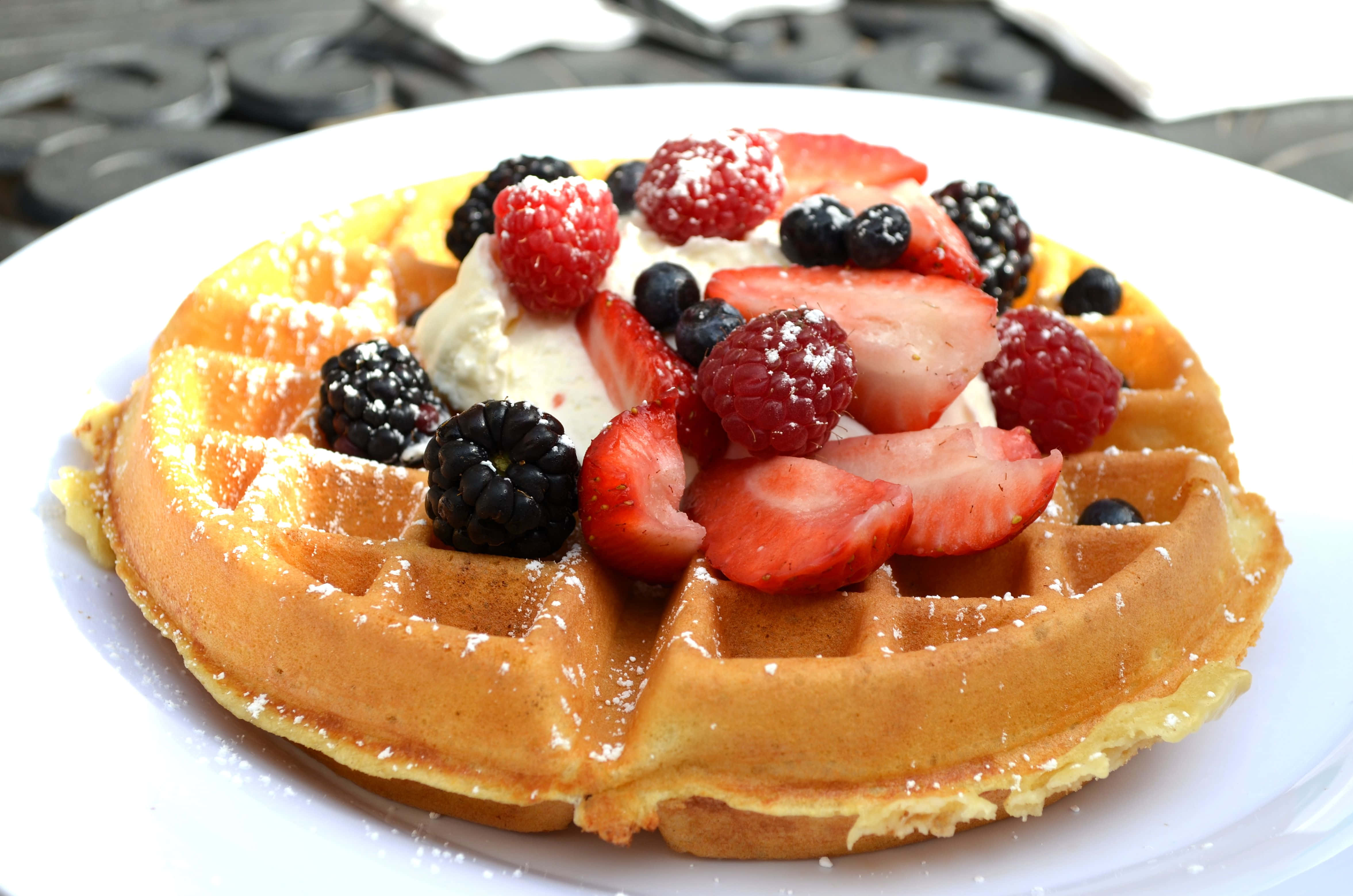Waffle 桌布 壁紙 — 金黃色窩夫配上新鮮莓果、忌廉和糖霜，放在白色碟上。