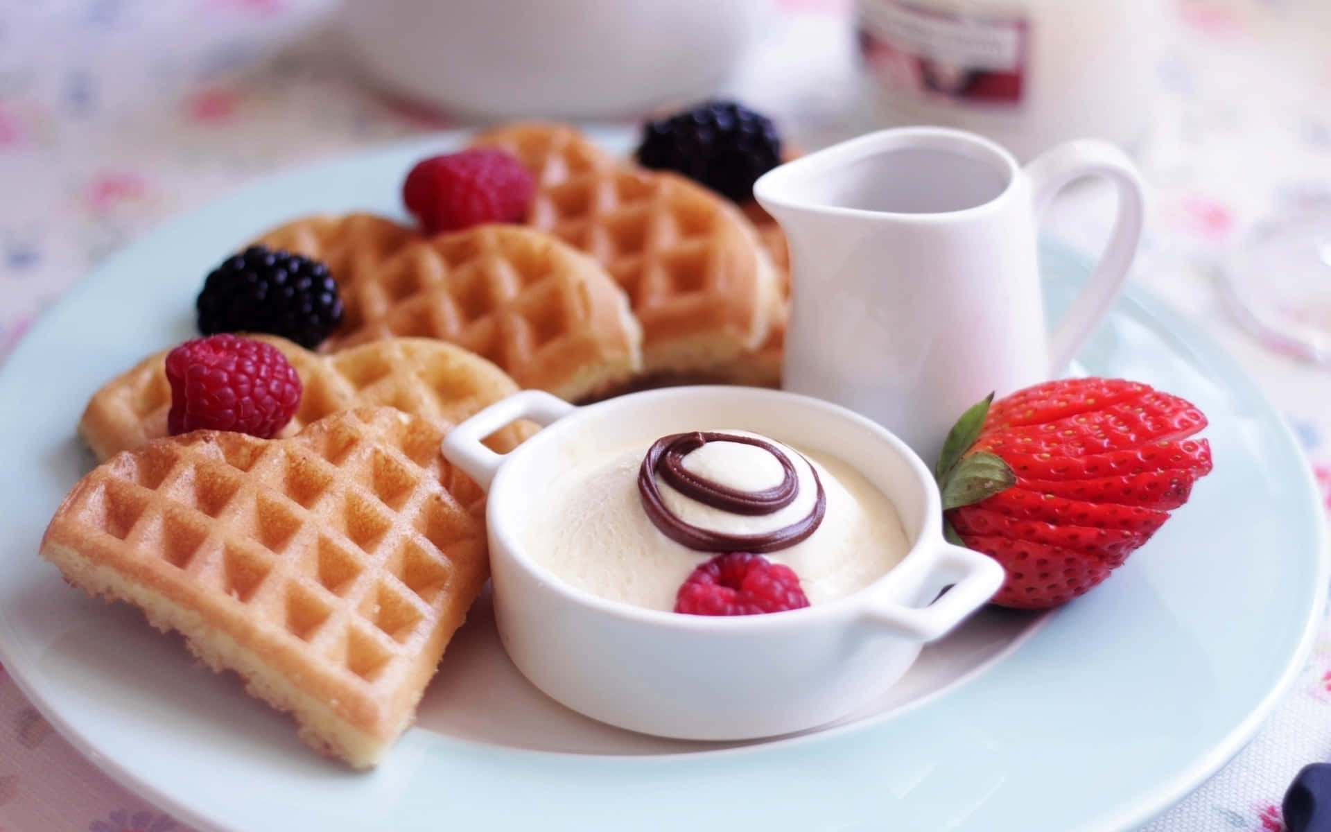 Waffle 桌布 壁紙 — 金黃色窩夫配上新鮮莓果和帶有朱古力漩渦的奶油甜品，放在淺藍色碟上。