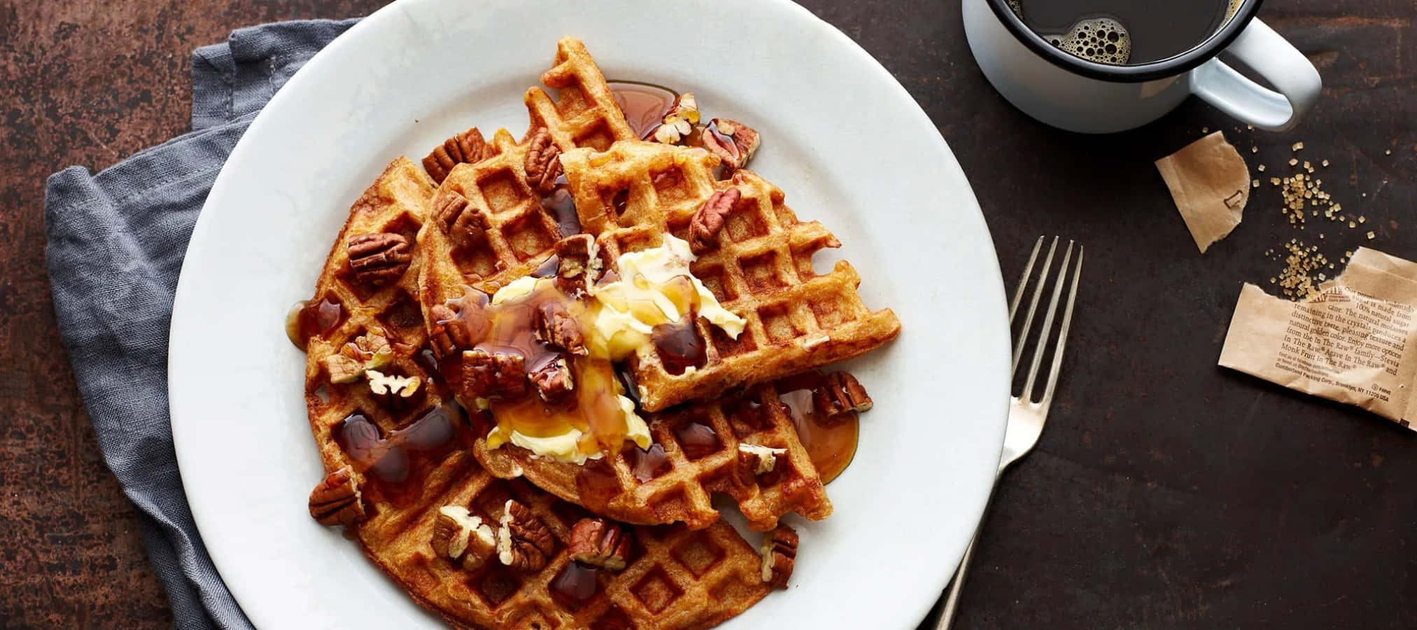 Waffle 桌布 壁紙 — 金黃色窩夫配上糖漿、牛油和山核桃，放在白色碟上，旁邊有咖啡杯和叉子，置於深色木桌上。