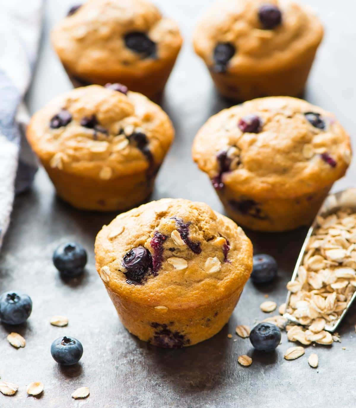 Blueberry Muffins 桌布 壁紙 — 金黃藍莓燕麥鬆餅，新鮮莓果和燕麥片散落在質樸的金屬表面上。