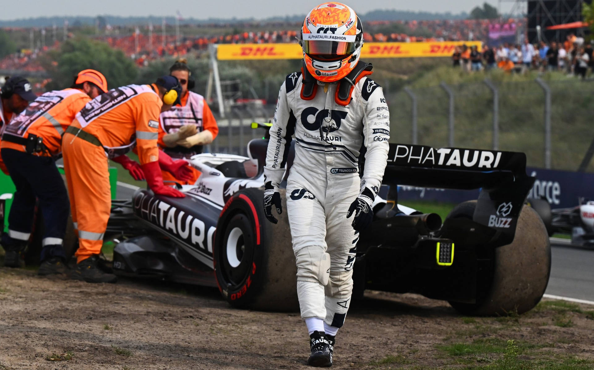 F1車手從受損的AlphaTauri賽車旁走開，維修人員正在處理。