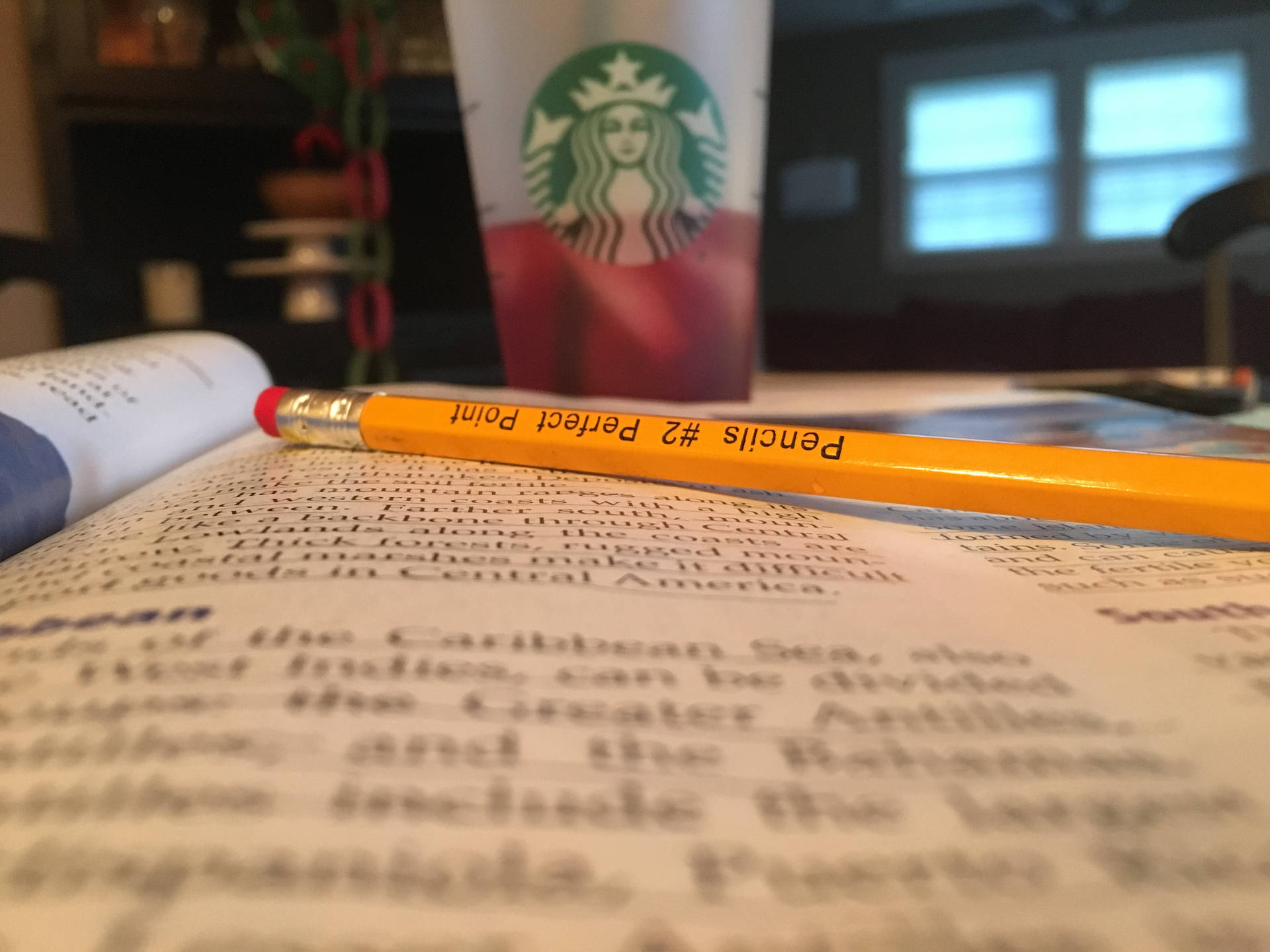 打開的教科書上的黃色鉛筆和桌上的 Starbucks 杯