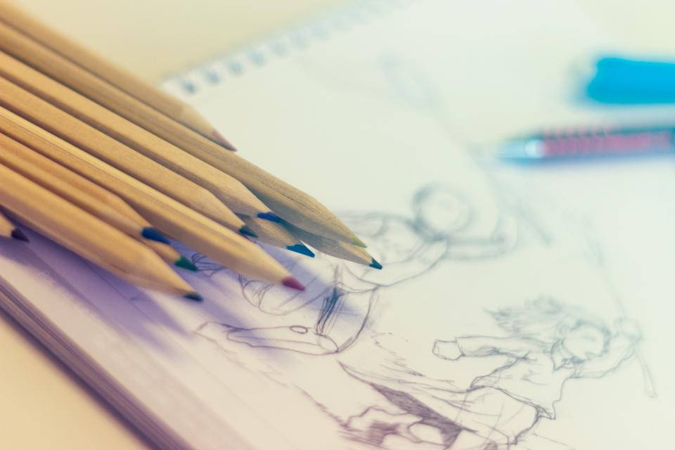 鉛筆草圖 壁紙 — 彩色鉛筆的特寫，放在一本有動漫角色繪圖的素描本上，背景柔和。