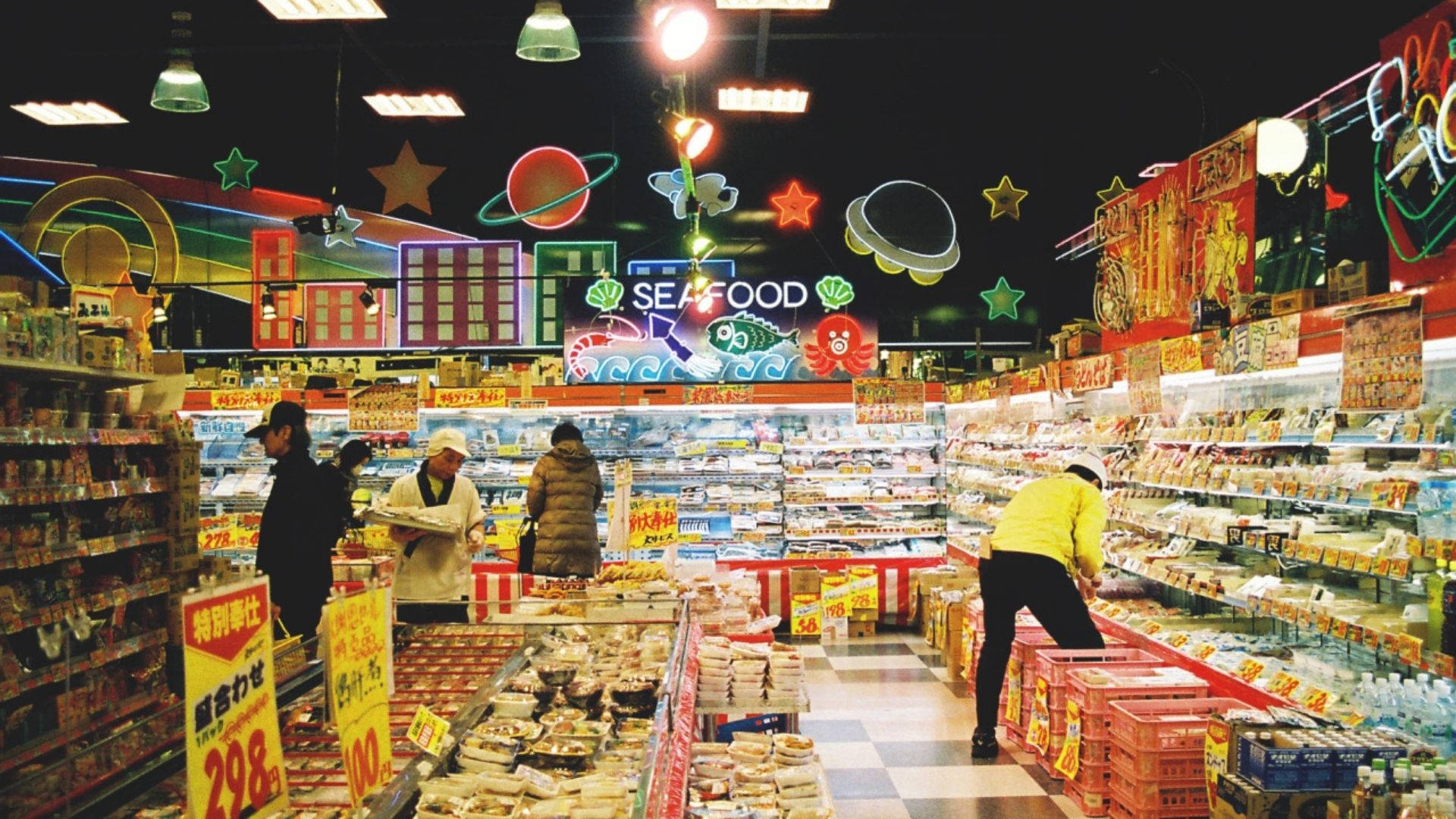銀河主題超市 壁紙 — 充滿活力的霓虹燈超市通道，顧客在色彩繽紛的天花裝飾下選購海鮮和小吃。