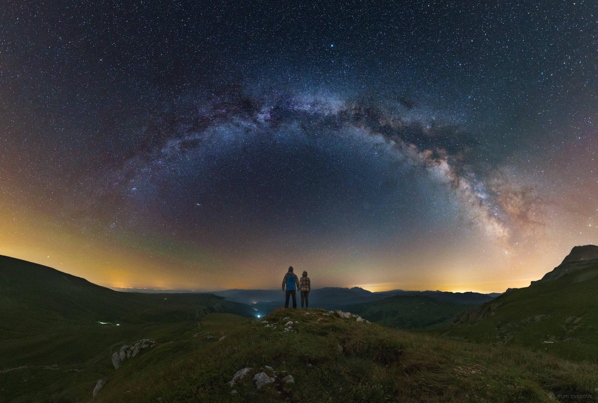 兩人在星空下的山脊上，銀河清晰可見。