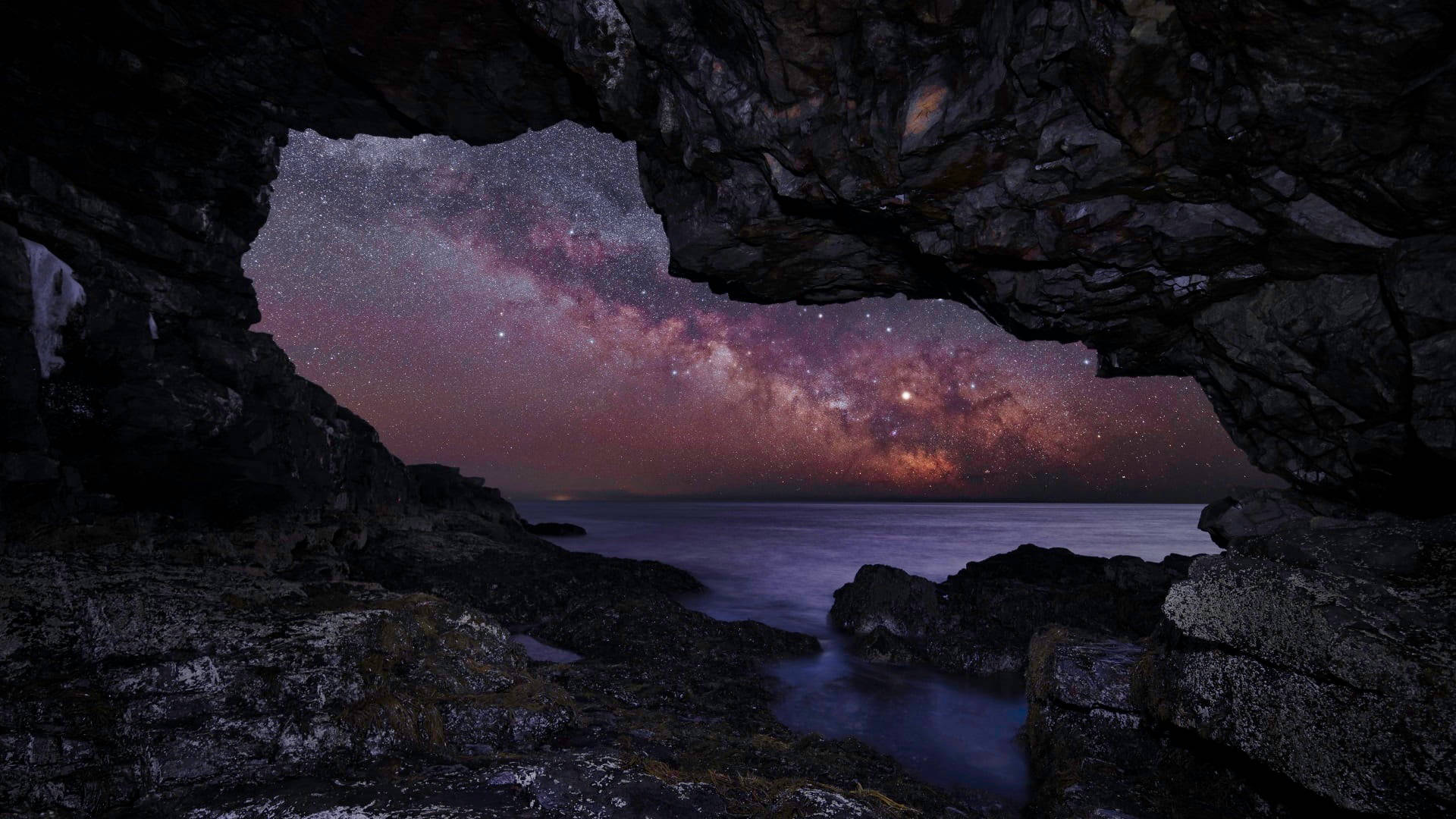 夜晚透過岩石海岸洞穴看到的銀河系。