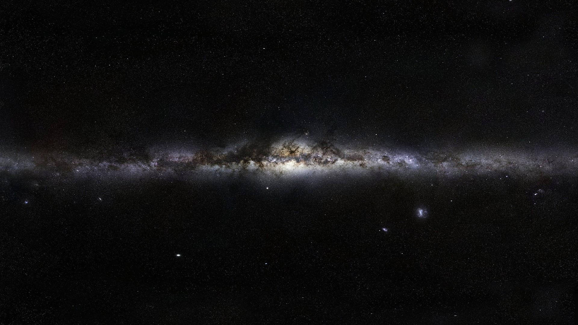銀河系在繁星點點的宇宙背景下，呈現出發光的星雲和黑暗的塵埃帶。