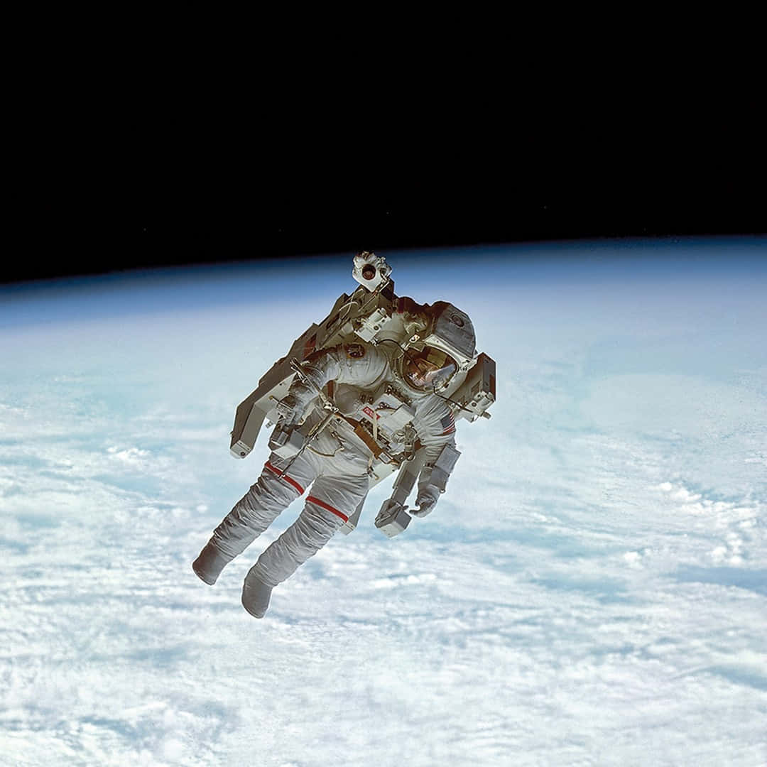 太空人在地球雲層覆蓋的表面上方太空中漂浮。