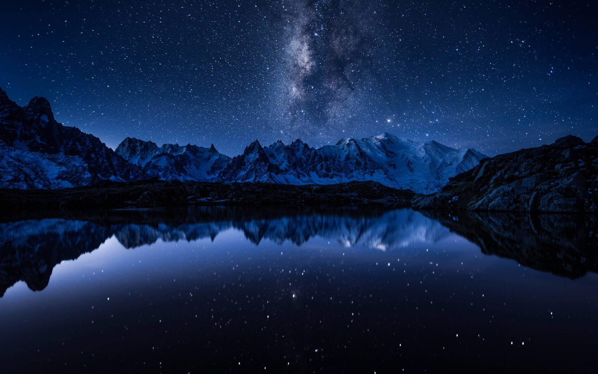 銀河系美學星系視角 壁紙 — 白雪覆蓋的山脈在繁星點點的夜空下，完美倒映在下方平靜的湖面上。