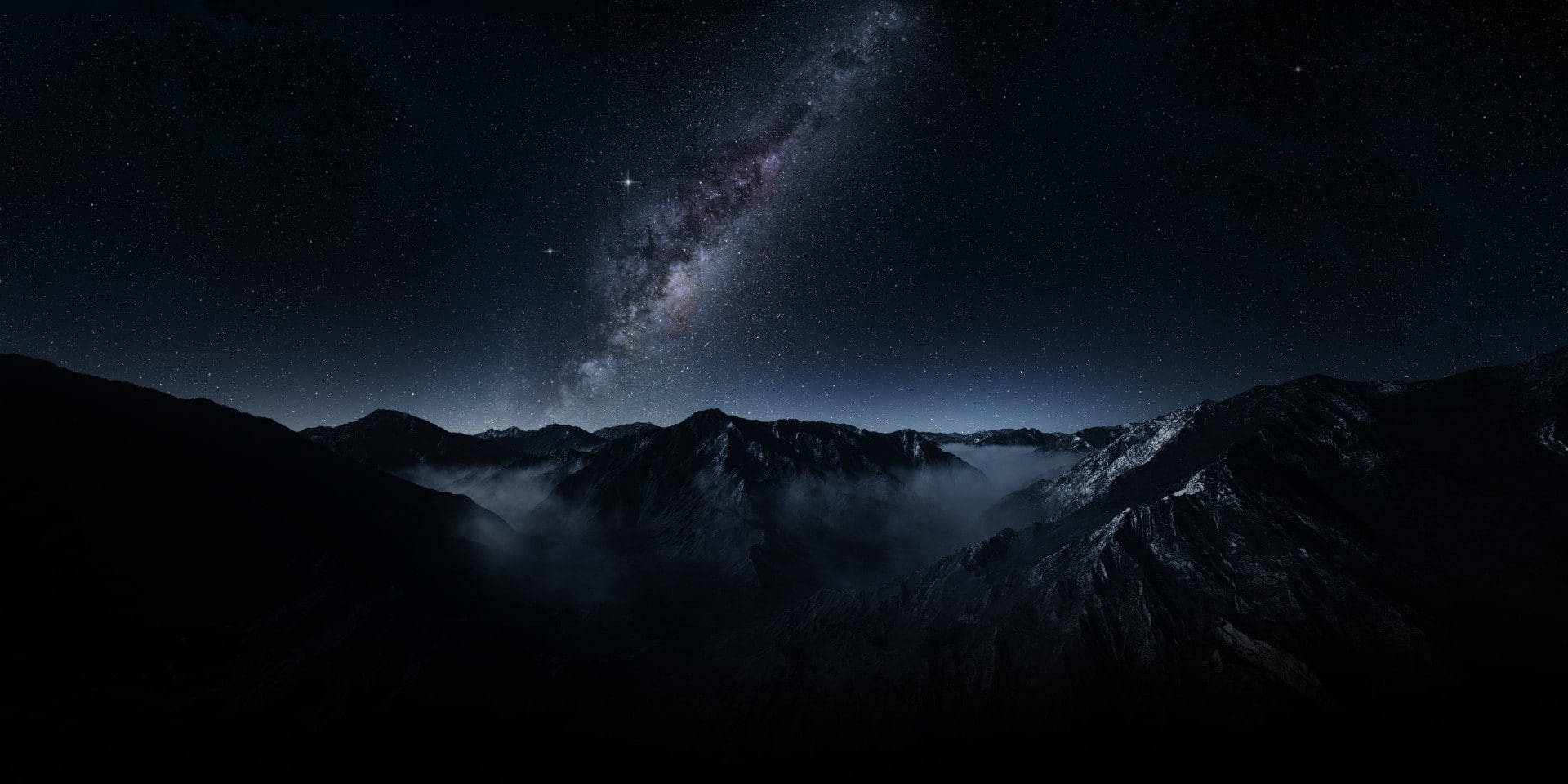 在滿天星斗的天空下，黑暗的山脈，銀河清晰可見。