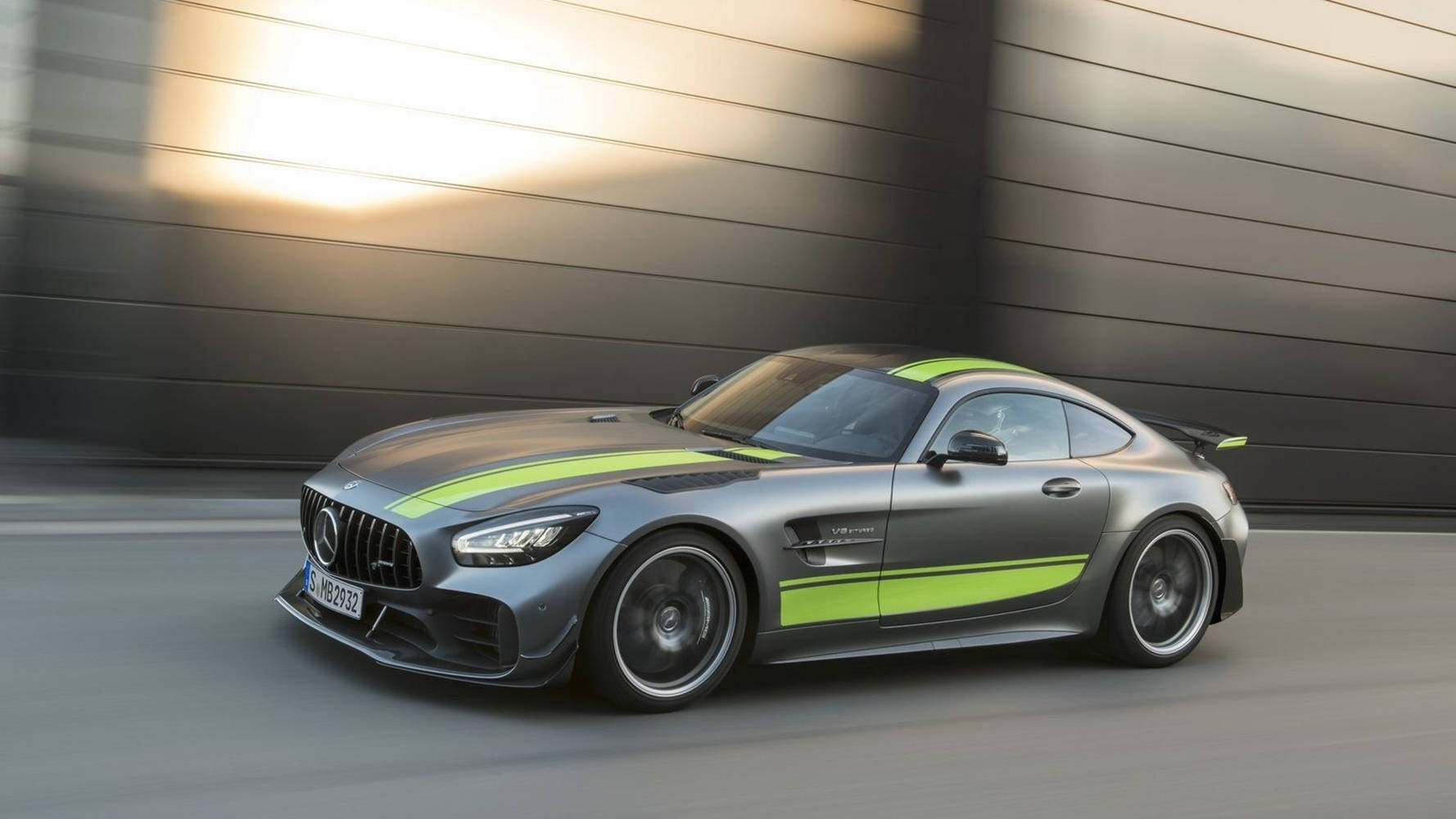 銀色 Mercedes-AMG GT R 帶有綠色賽車條紋在道路上疾馳。