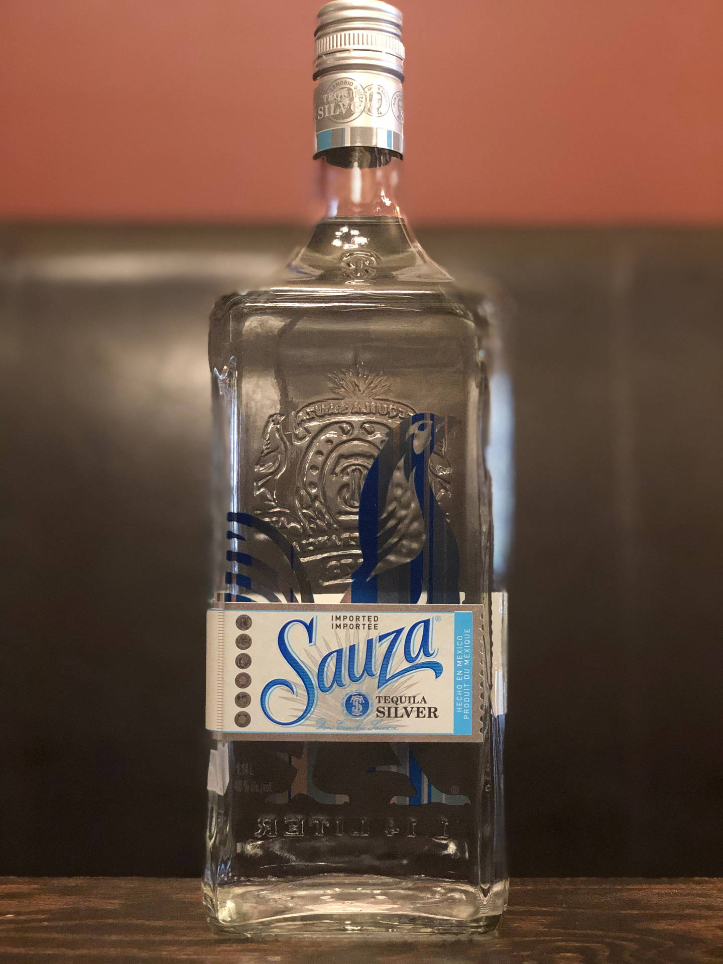 Sauza Silver Tequila 酒瓶在木吧台上，暖色背景
