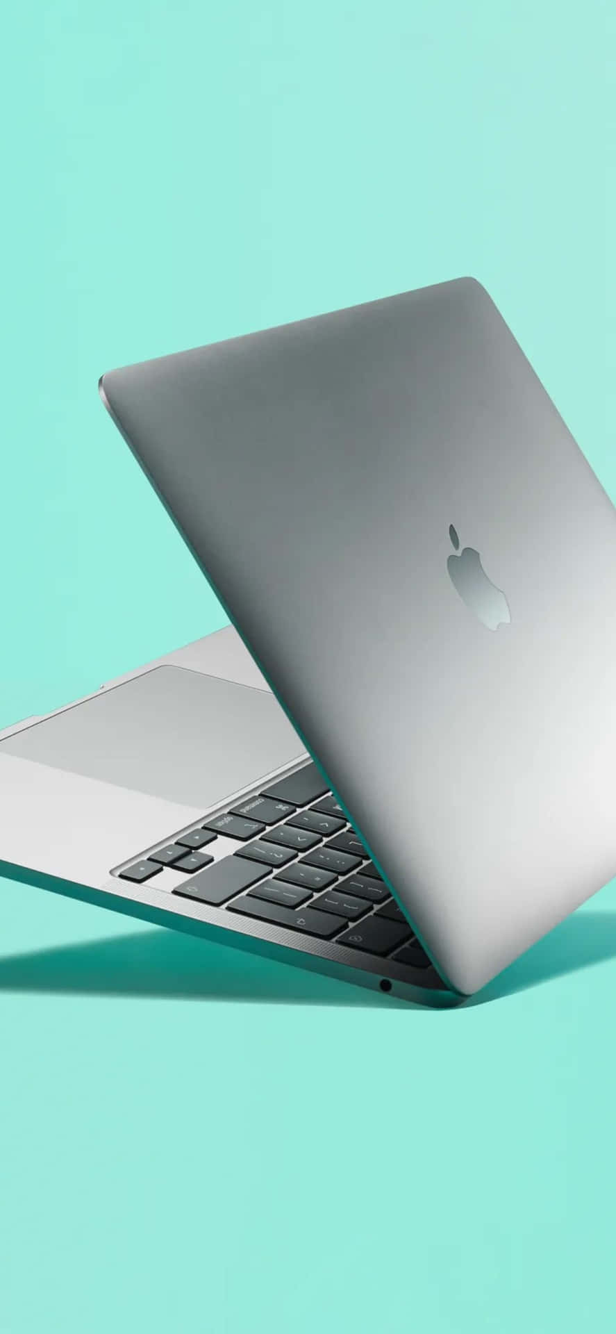銀色 MacBook 手提電腦在薄荷綠色背景上打開