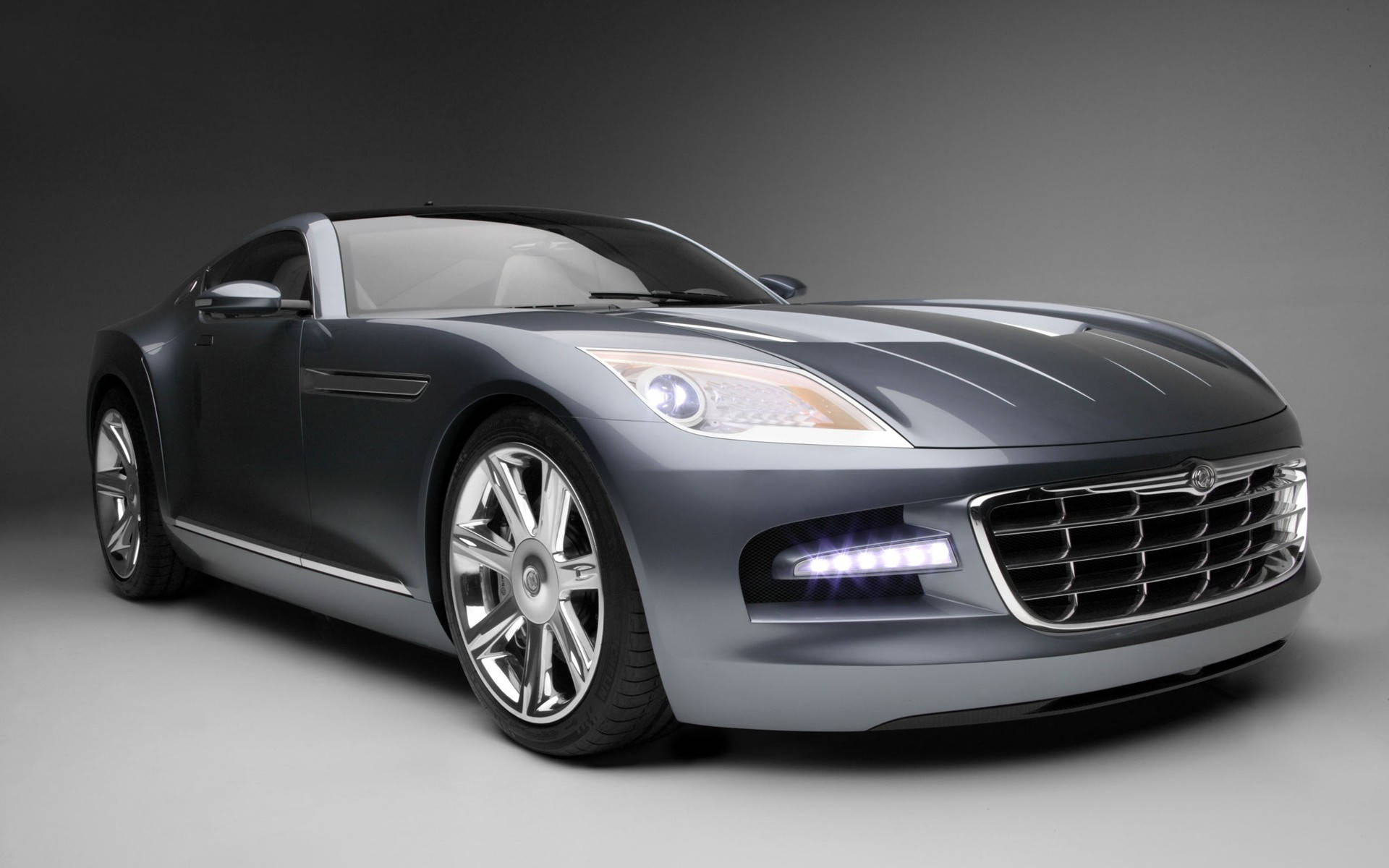 銀色 Chrysler Crossfire 壁紙 — 一輛時尚的銀色跑車，配備發光頭燈和鍍鉻輪圈，在灰色中性攝影棚背景前擺拍。