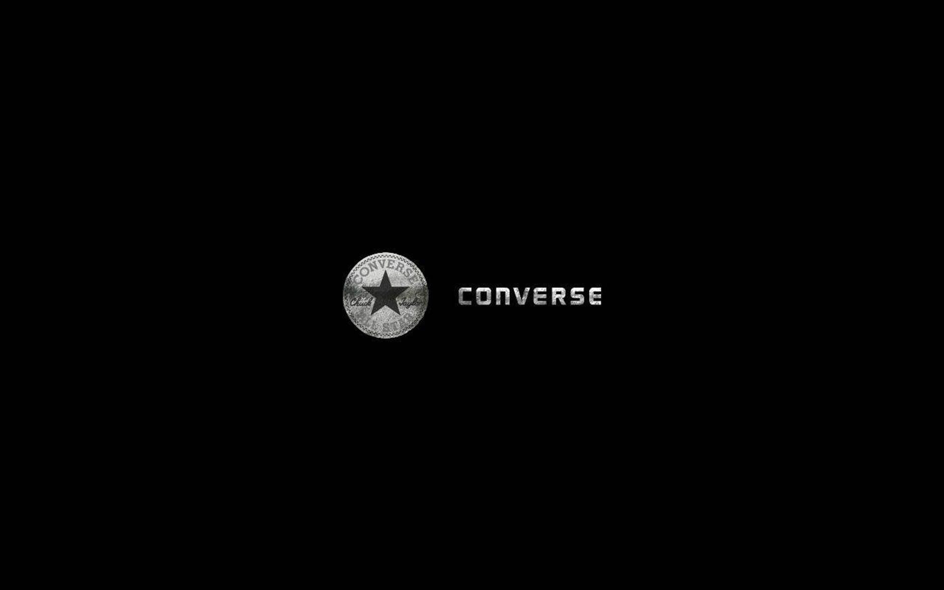 銀色 Converse 標誌 壁紙 — 簡約黑色背景上，經典的Converse標誌以金屬銀色呈現，包含星形徽章和品牌名稱。