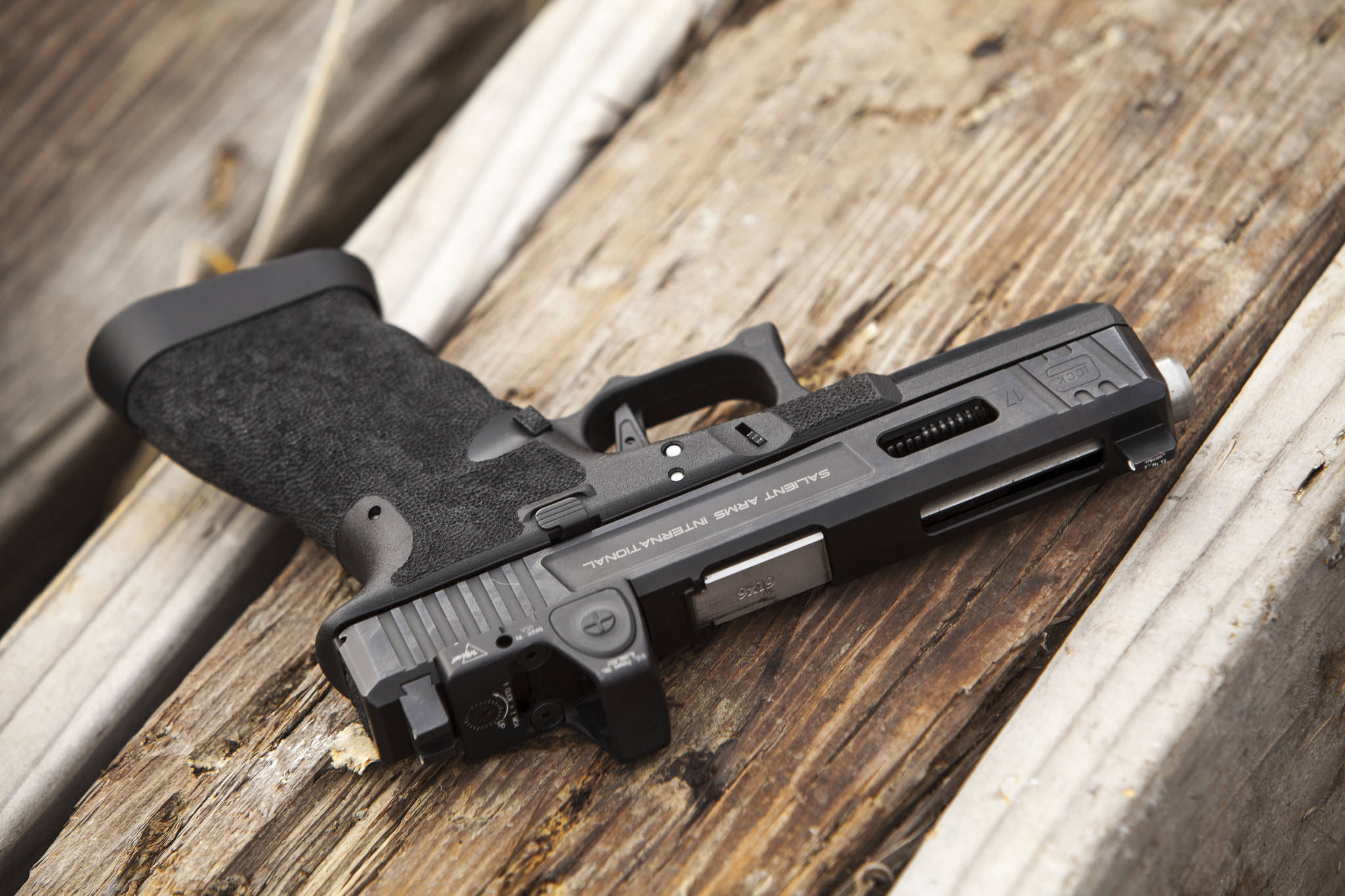 銀色 muzzle 的 Glock 17 壁紙 — 一把黑色半自動手槍放在經風化的木板上，帶有細緻紋理和自然光線。