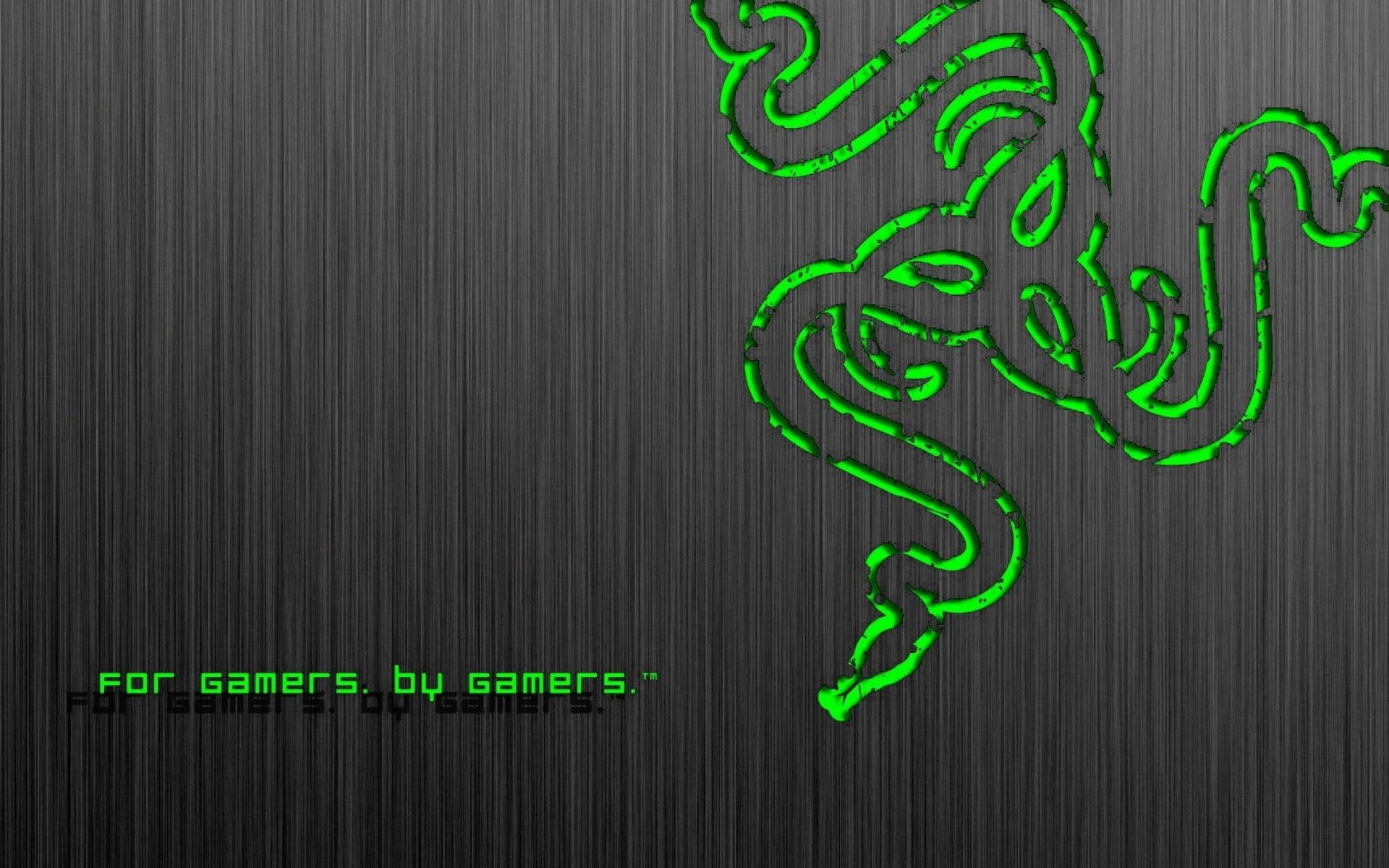 銀色 Razer PC 標誌與口號 壁紙 — 發光綠色Razer標誌蜿蜒在拉絲金屬紋理上，並以匹配的綠色顯示「for gamers by gamers」標語。