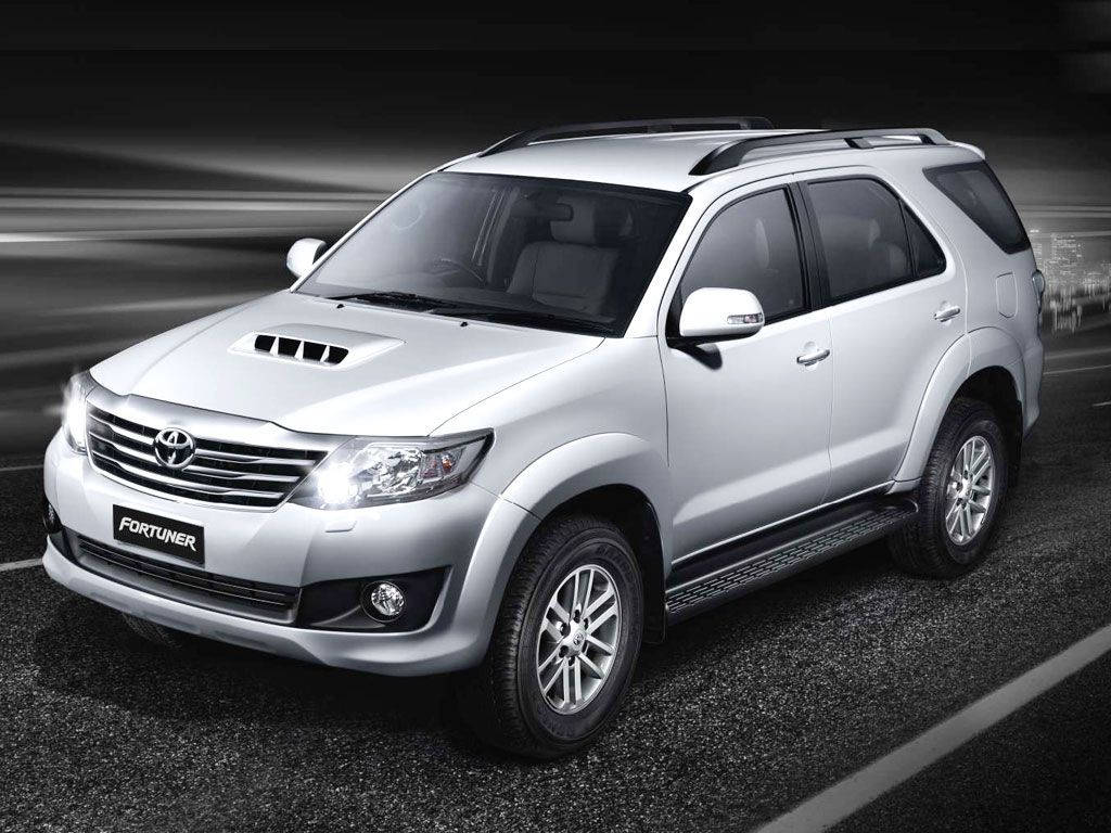 銀色豐田 Fortuner SUV 在黑暗的道路上行駛，帶有動態模糊效果。
