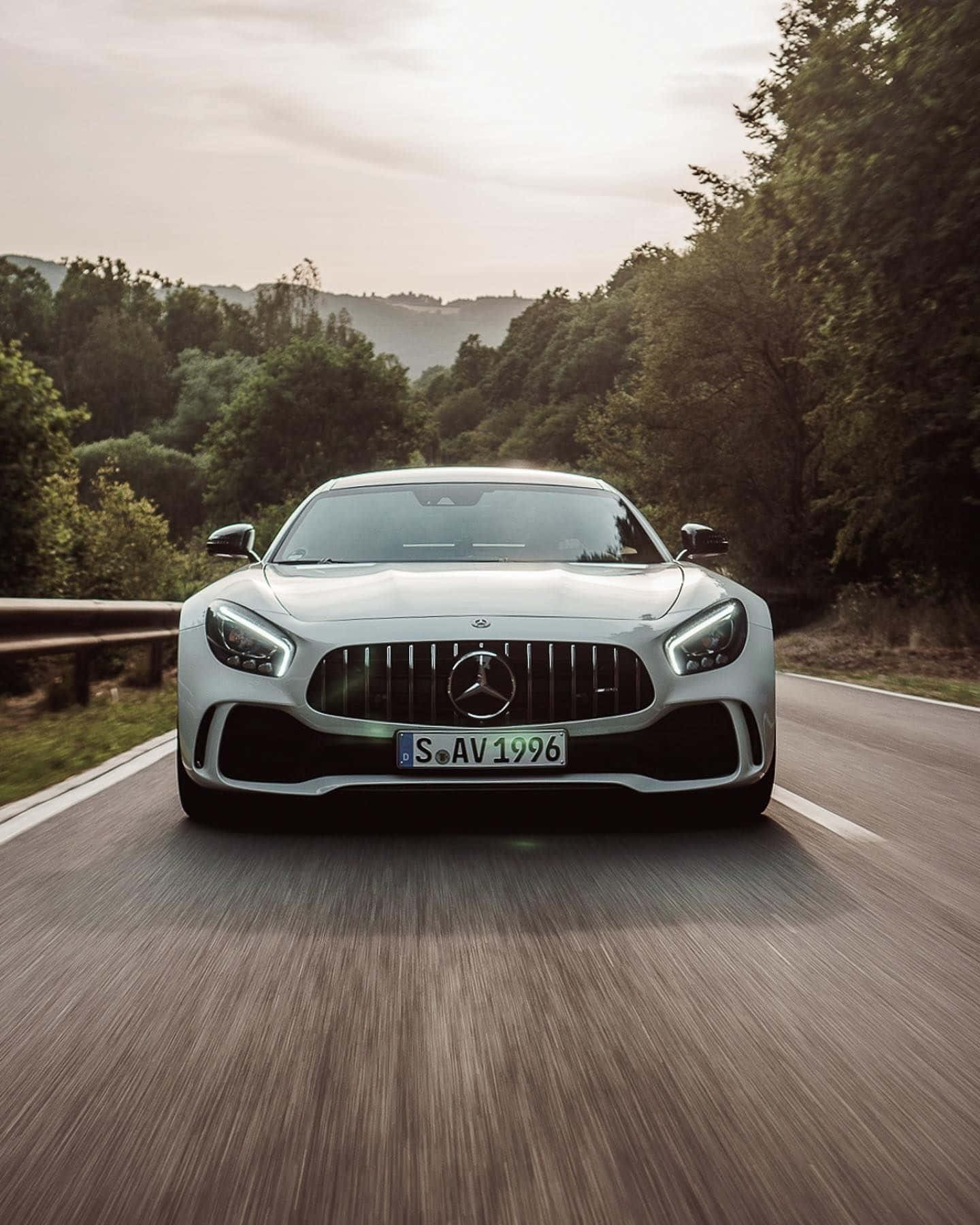 銀色AMG GT-R森林背景壁紙 壁紙 — 一輛銀色Mercedes-AMG GT跑車在蜿蜒的森林道路上疾馳，瀝青路面上呈現動態模糊效果。