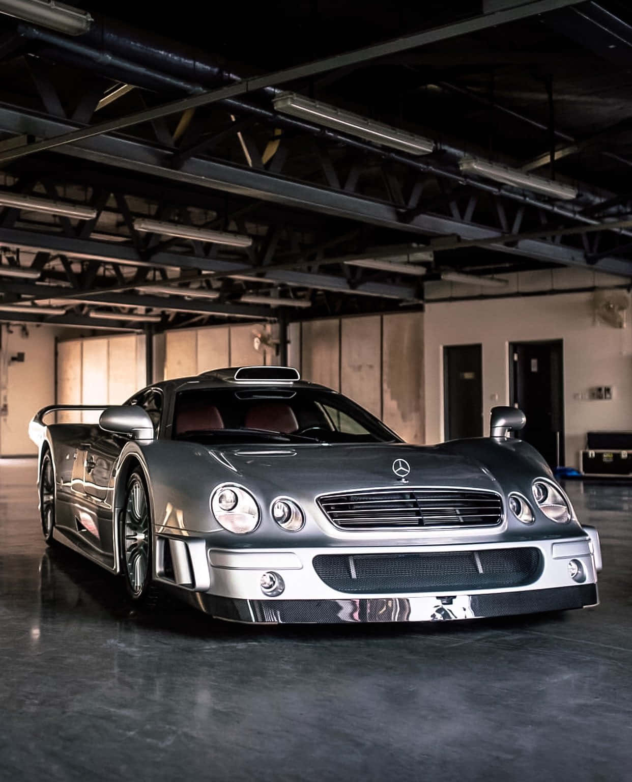 銀色AMG GT-R車庫安卓背景 壁紙 — 一架時尚的銀色 Mercedes-Benz CLK GTR 跑車在寬敞的混凝土車庫中，於工業照明下閃閃發光。