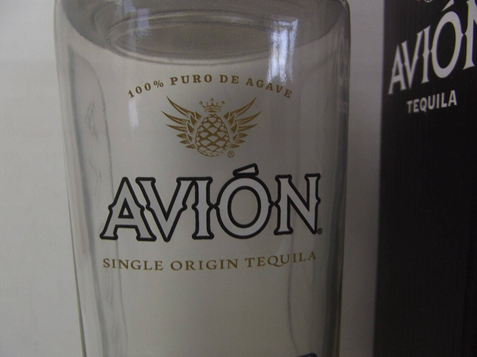 Avión龍舌蘭酒杯和酒瓶，帶有金色和黑色品牌標識。