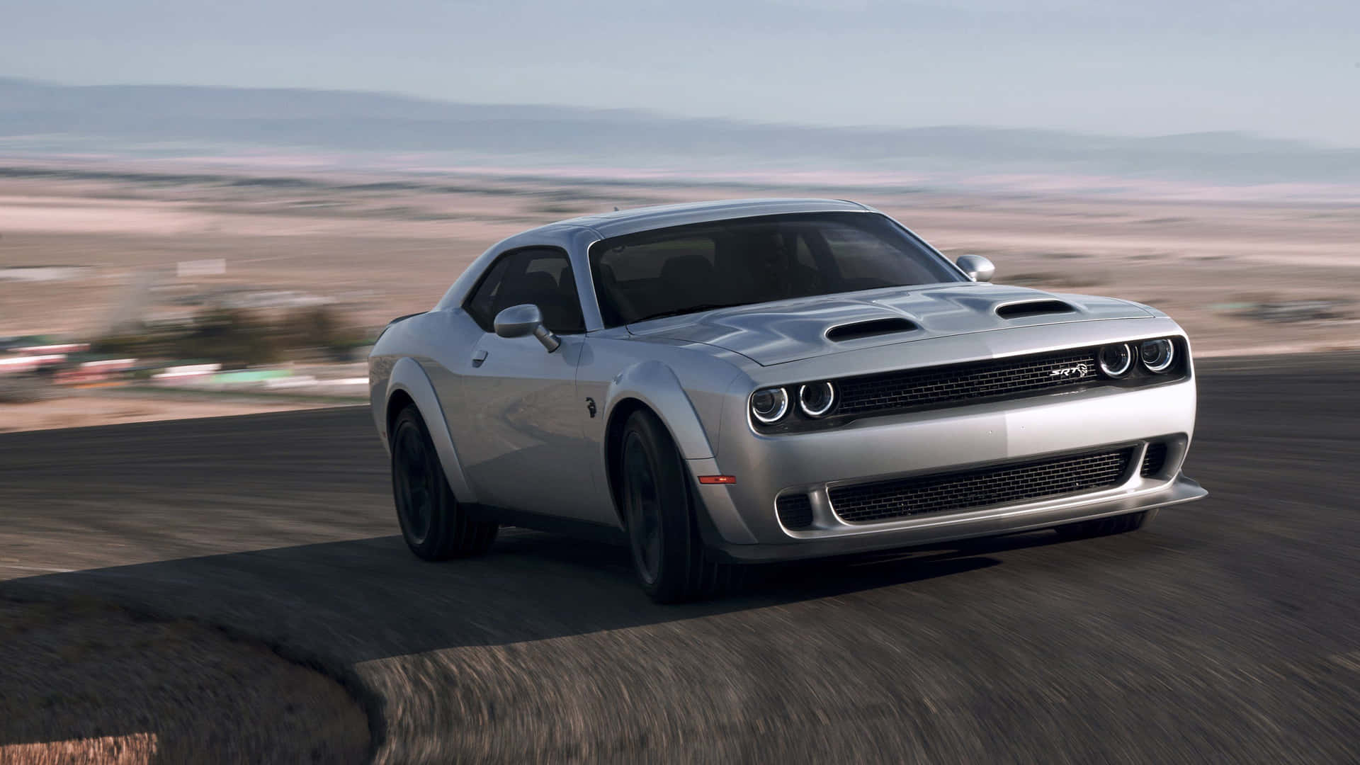 銀色 Dodge Challenger SRT Hellcat 在沙漠公路上奔馳。