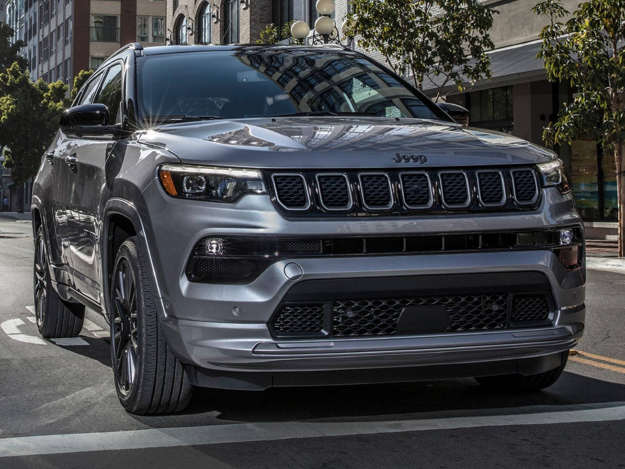 銀色Jeep Grand Cherokee停泊在城市街道上，有建築物和樹木。