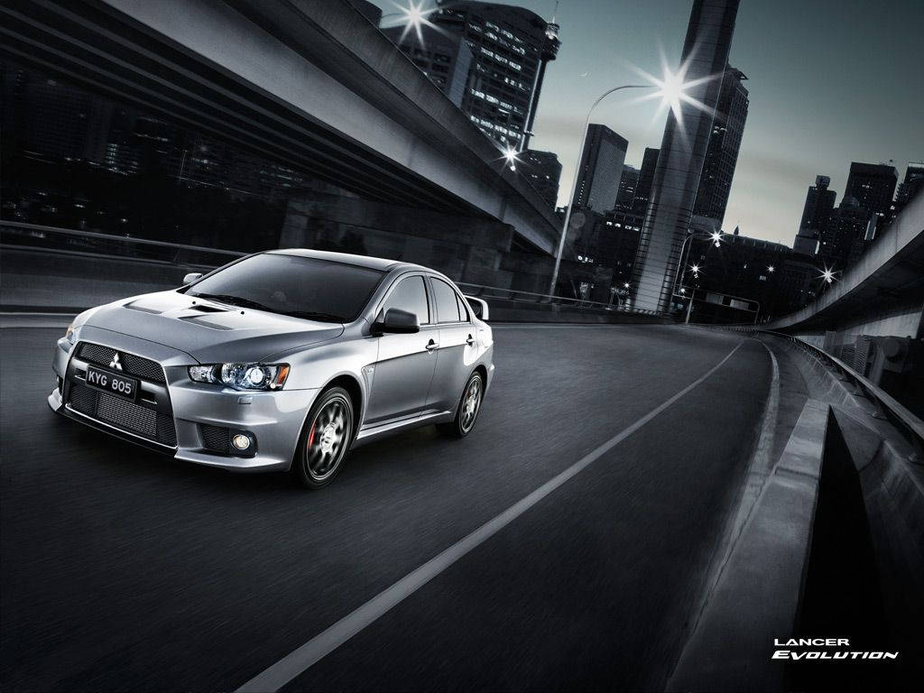 銀色三菱Lancer Evolution在黃昏時分在城市高速公路上疾馳。