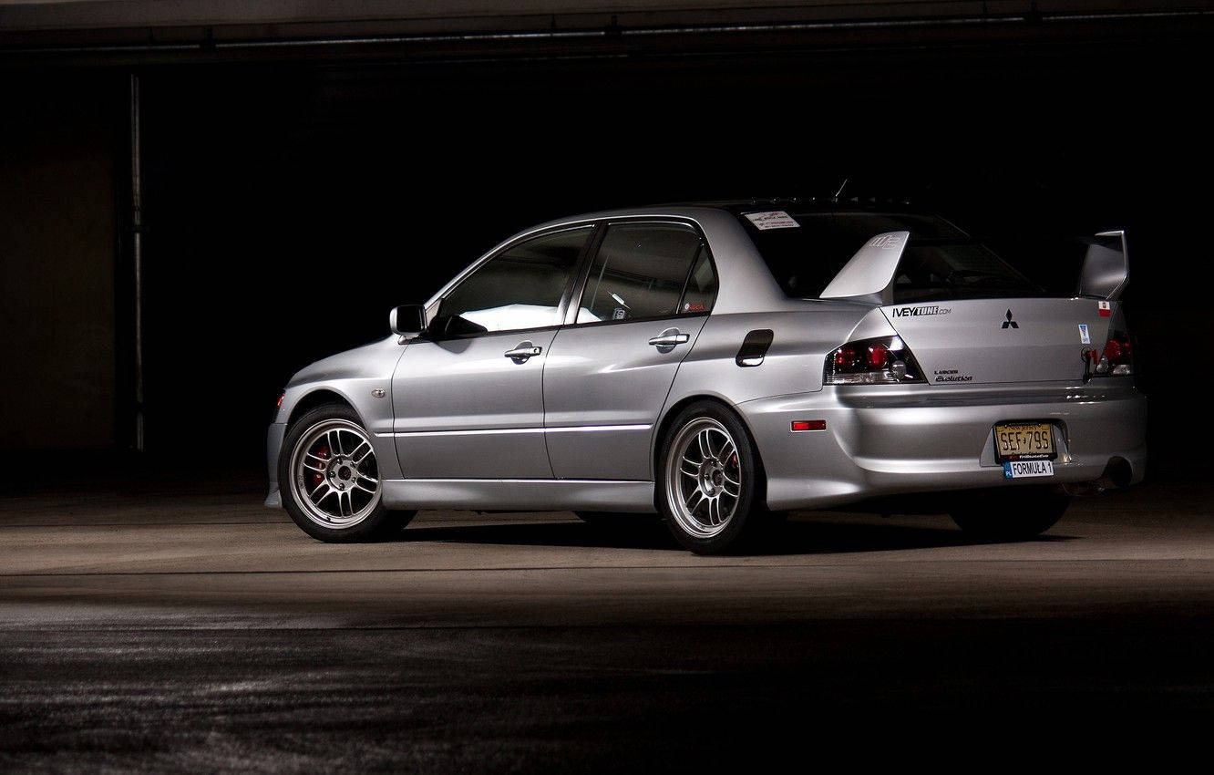 銀色三菱Lancer Evolution在黑暗車庫中，聚光燈照射。