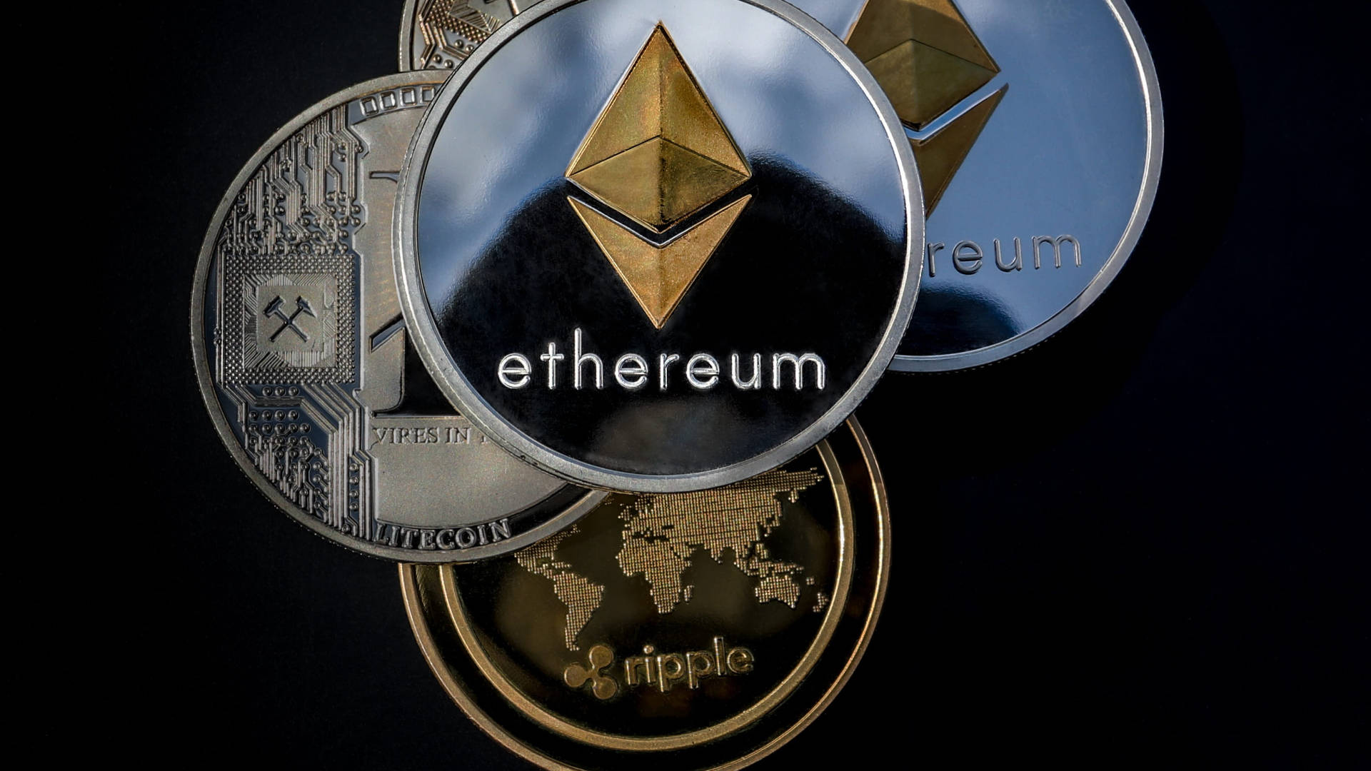 銀色以太幣硬幣 壁紙 — 閃亮的加密貨幣硬幣，包括以太坊、萊特幣和瑞波幣，排列在黑色背景上。