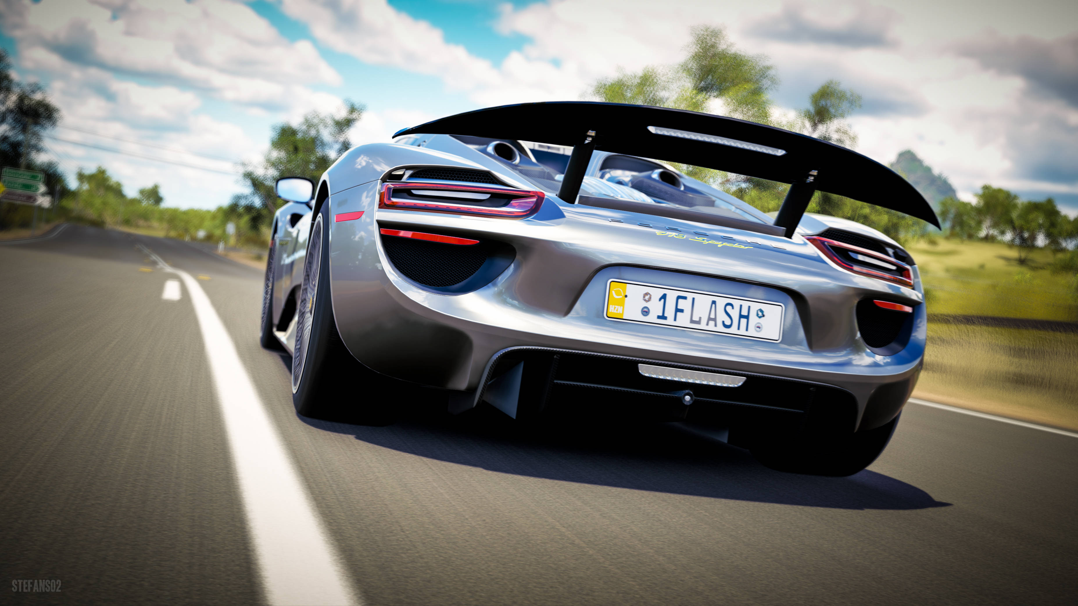 銀色保時捷 Forza Horizon 3 壁紙 — 一輛銀色保時捷918 Spyder在陽光明媚的鄉間道路上疾馳，帶有大型後擾流板和模糊的綠植。