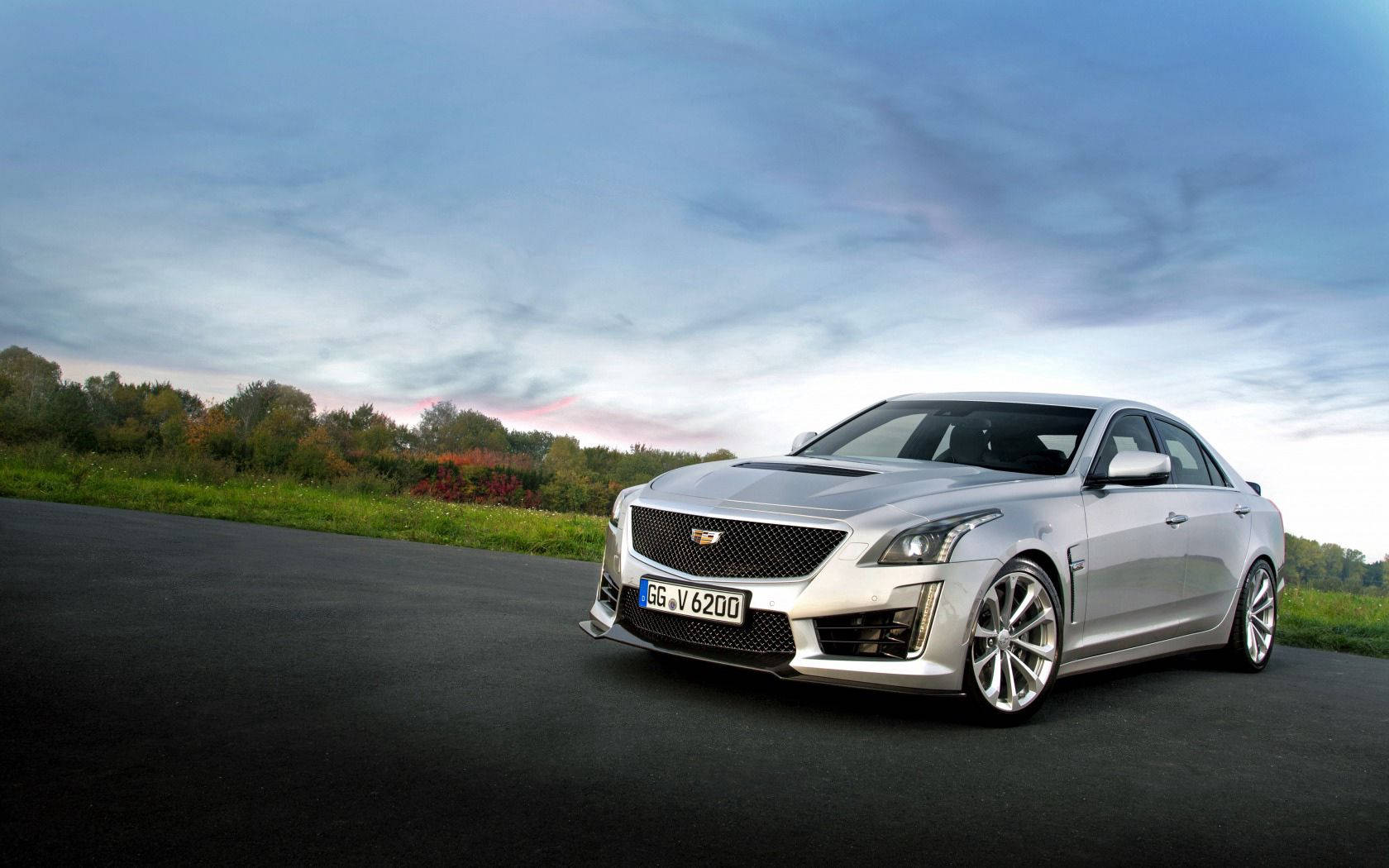 銀色Cadillac CTS-V房車停泊在黃昏的路上，背景有秋葉。