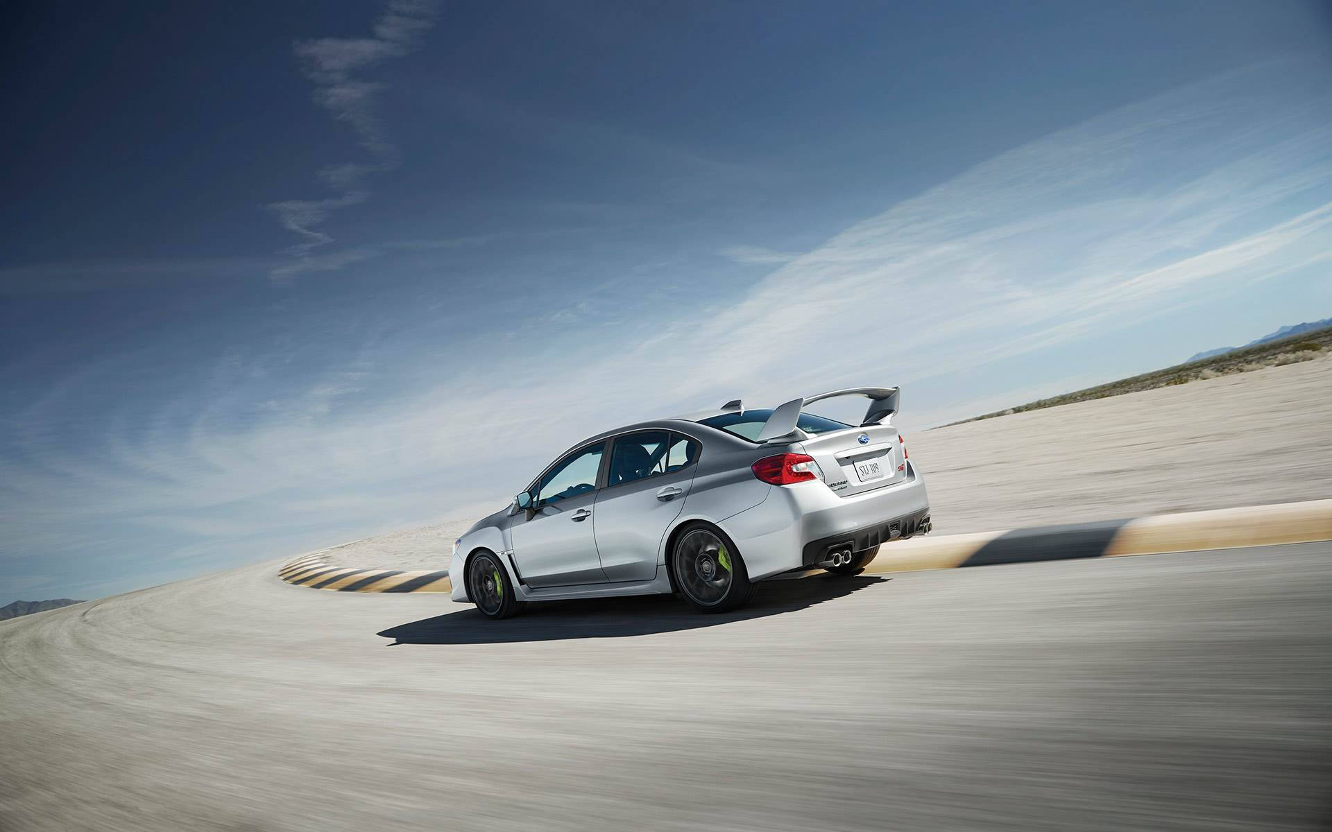 銀色塗裝斯巴魯Impreza 壁紙 — 一架銀色Subaru WRX STI在晴朗藍天下，以動態模糊效果在沙漠賽道上飛馳。