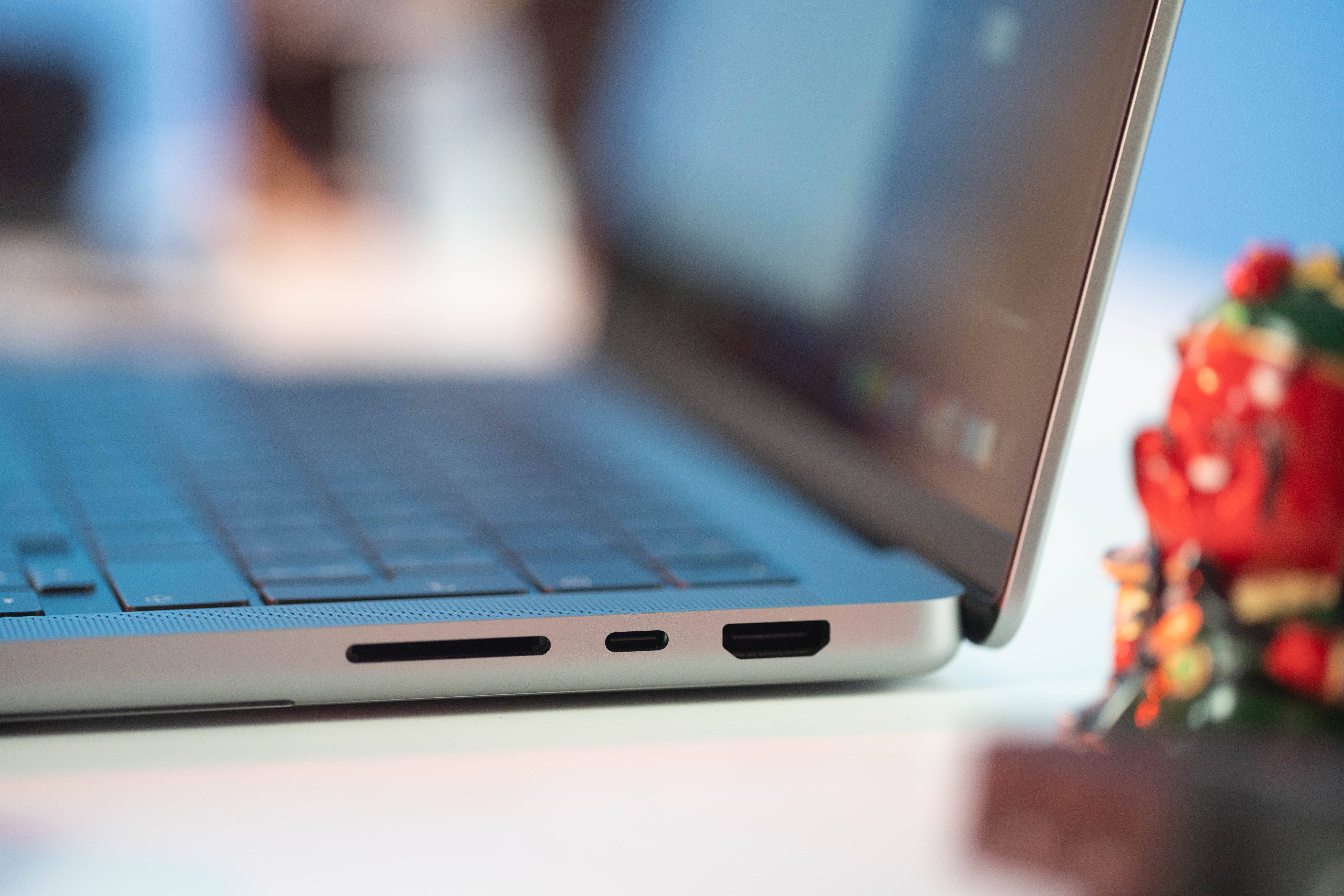 Surface Book 3 壁紙 — 銀色手提電腦側面接口的特寫，背景中有一個色彩繽紛的公仔模糊可見。