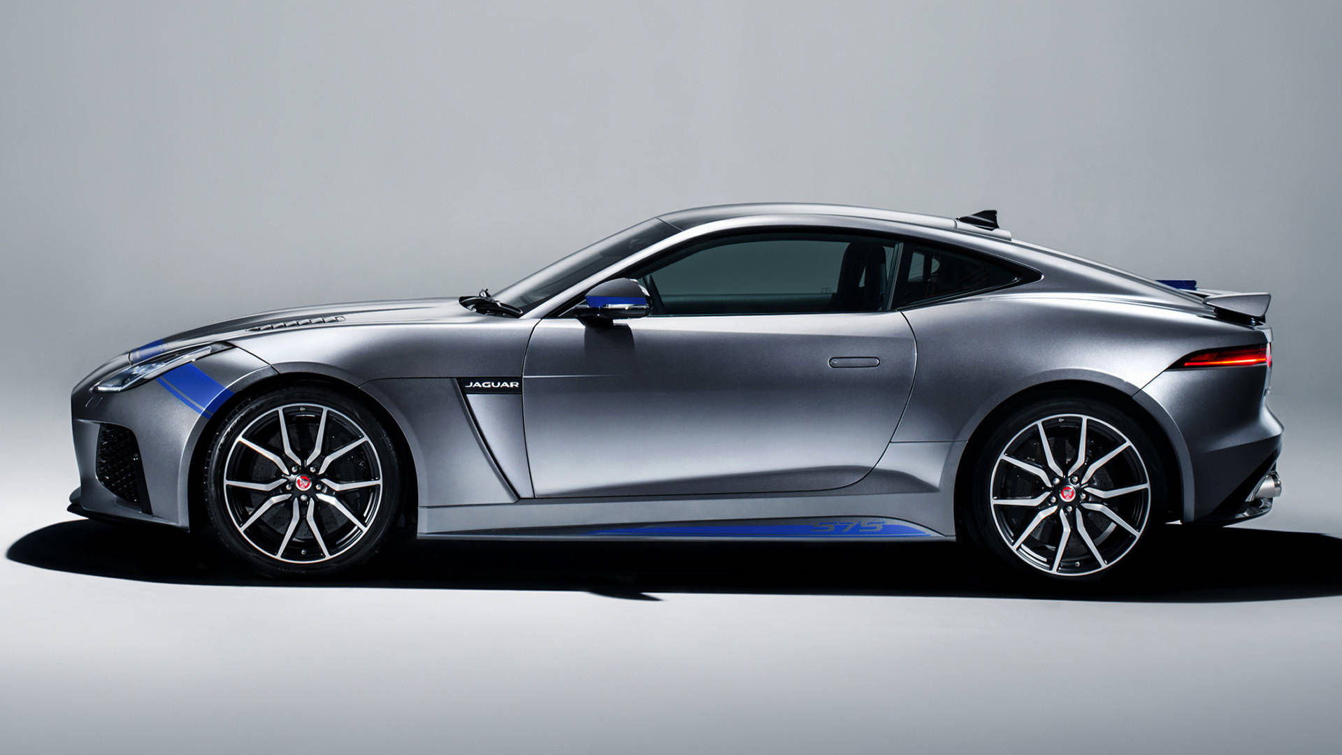 銀色捷豹F-Type側面圖 壁紙 — 一輛時尚的銀色 Jaguar F-Type 跑車帶有藍色點綴，在極簡灰色工作室背景中以側面輪廓展示。