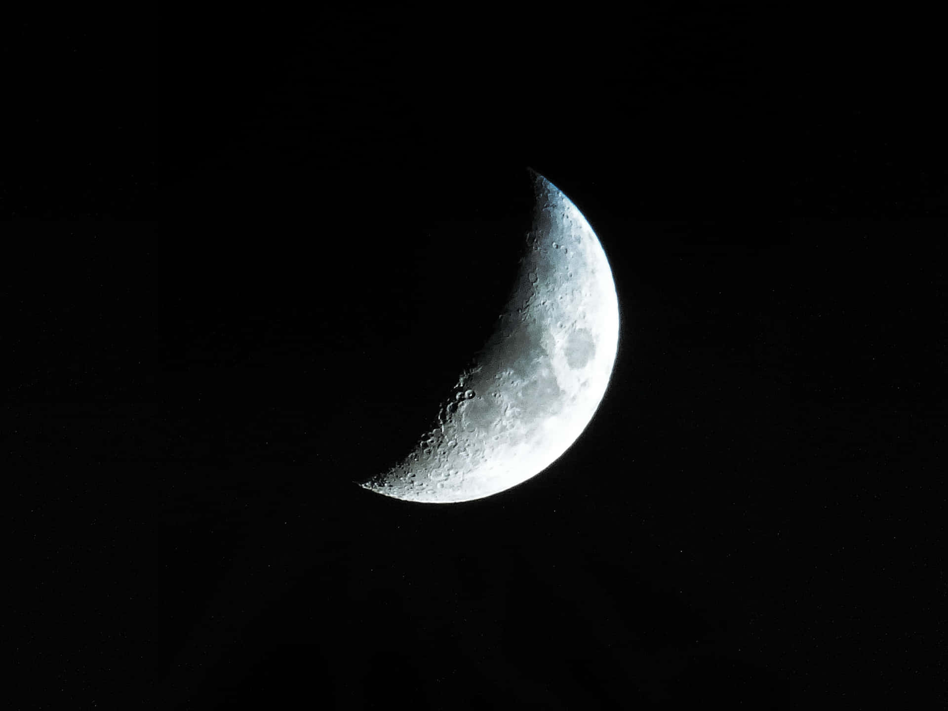 銀色新月圖 壁紙 — 一個細節清晰的彎月，在點綴著微弱星光的深黑夜空下閃耀。