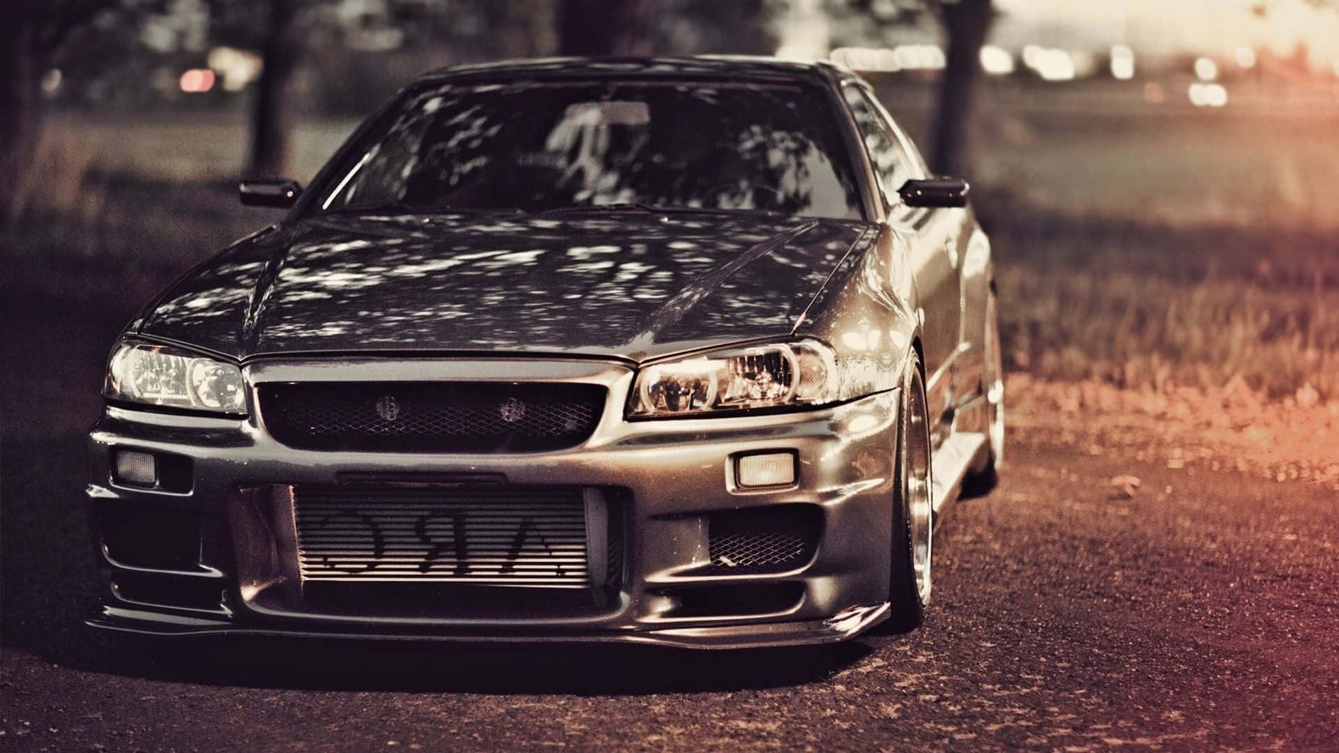 銀色日產Skyline R34飄移車停泊在碎石路上，正值黃金時段。