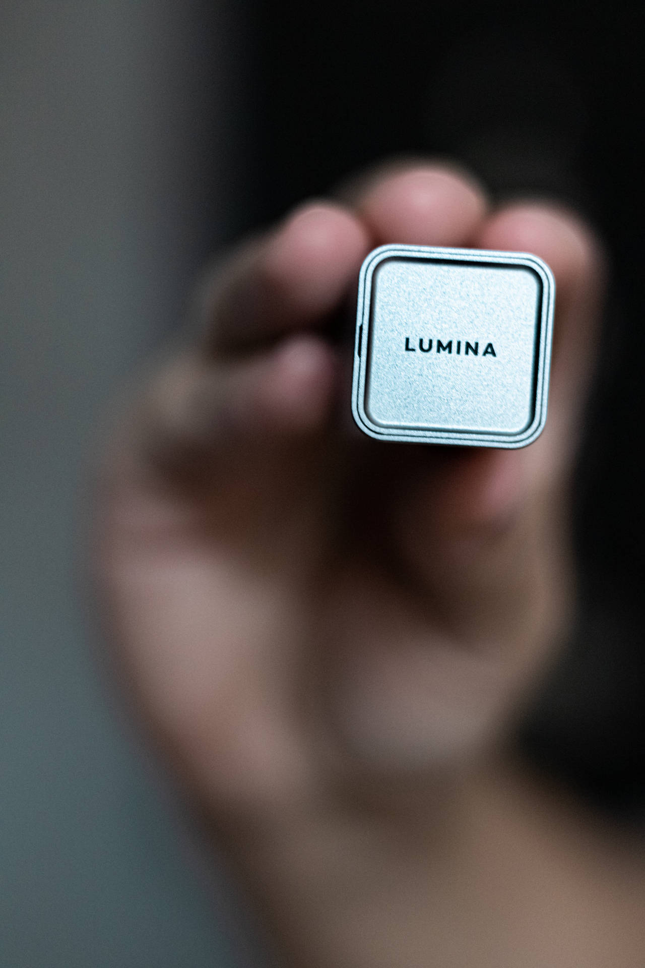 手拿著一個標有LUMINA的小型銀色方形裝置