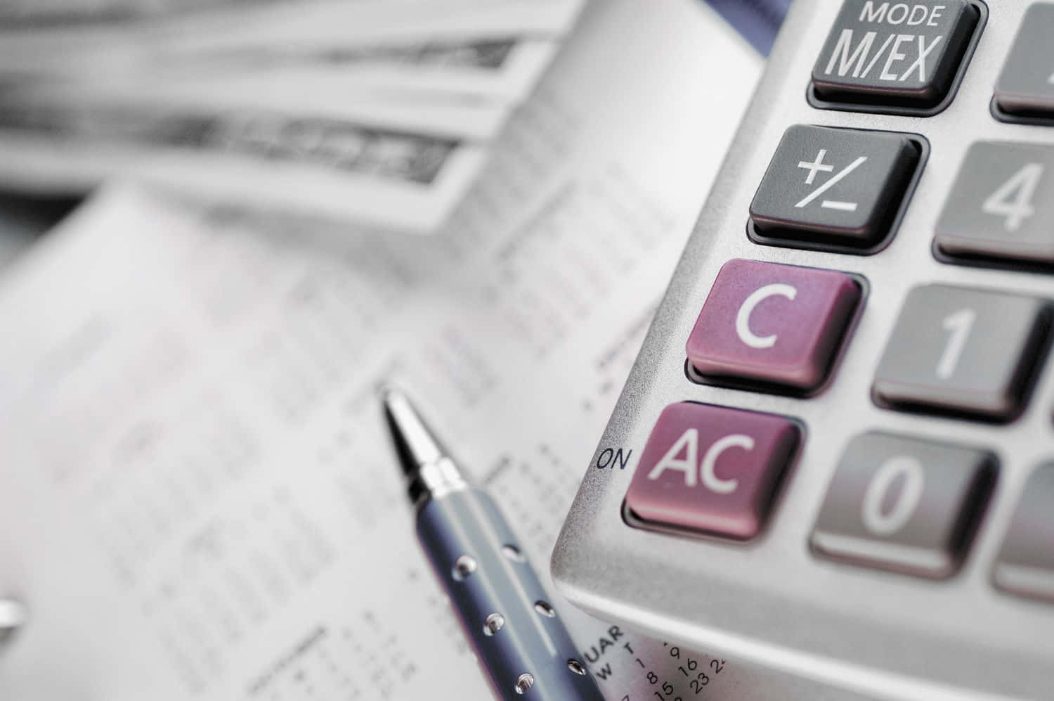 Calculator 桌布 壁紙 — 銀色計算器特寫，帶有紫色功能鍵，放在財務文件上，附近有一支筆。