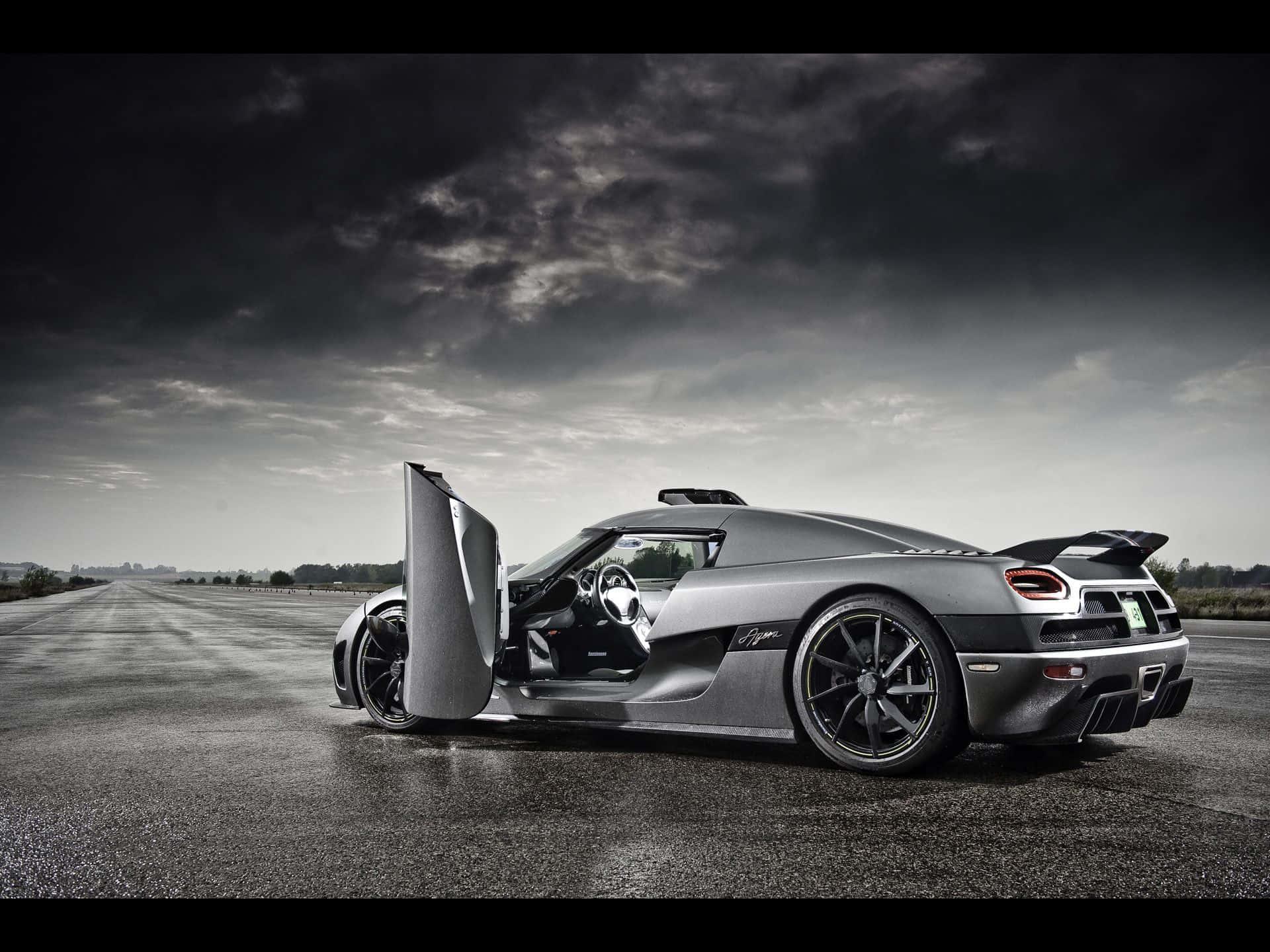 銀色Koenigsegg Agera超跑，剪刀門打開，在暴風雨天空下的空路上。