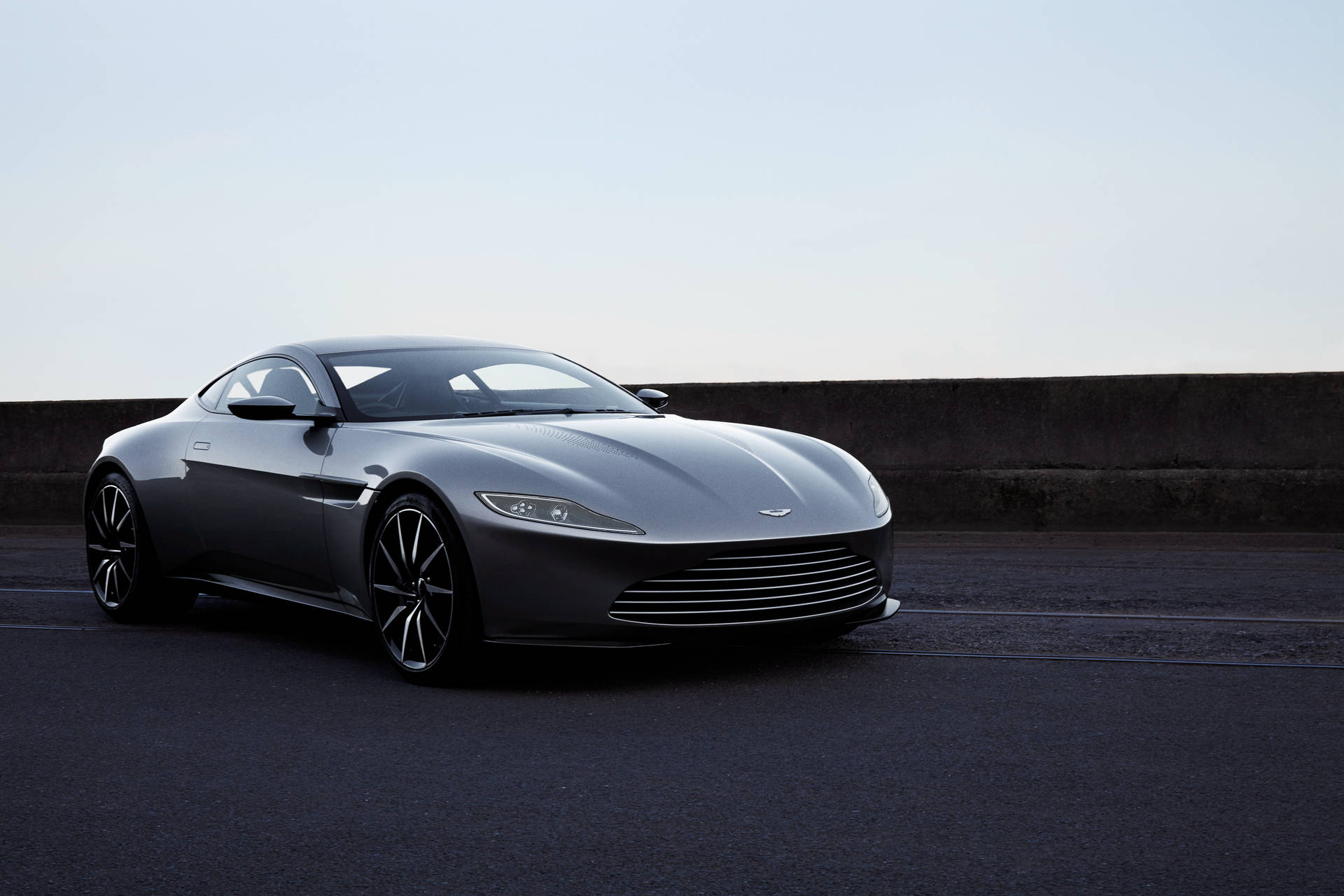 銀色Aston Martin跑車停泊在瀝青路上，靠近混凝土護欄。