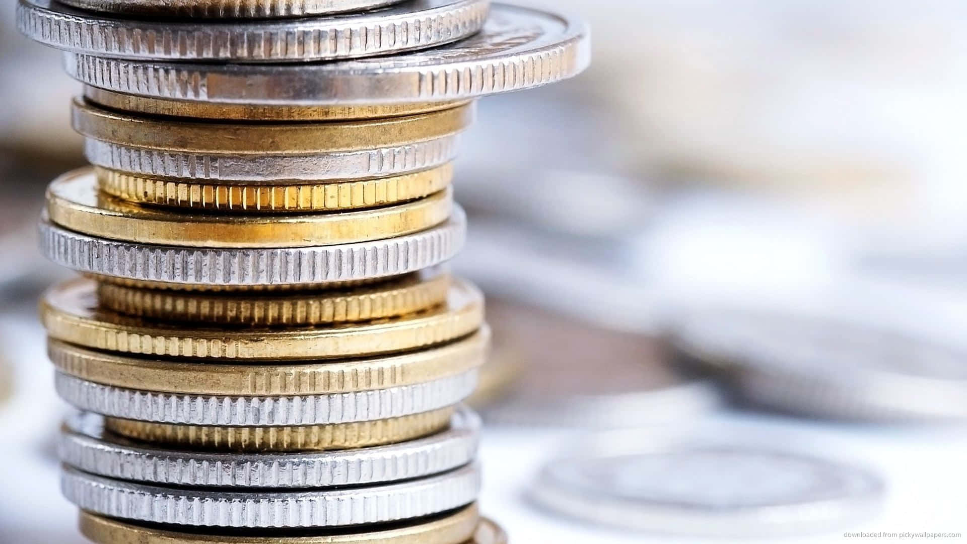 銀金幣疊放 壁紙 — 一堆高聳的金幣和銀幣，邊緣鋒利，在模糊的散落硬幣背景中清晰可見。