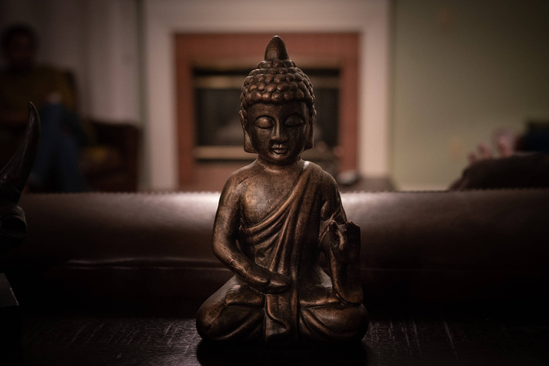 昏暗房間中的青銅佛像，背景家具模糊